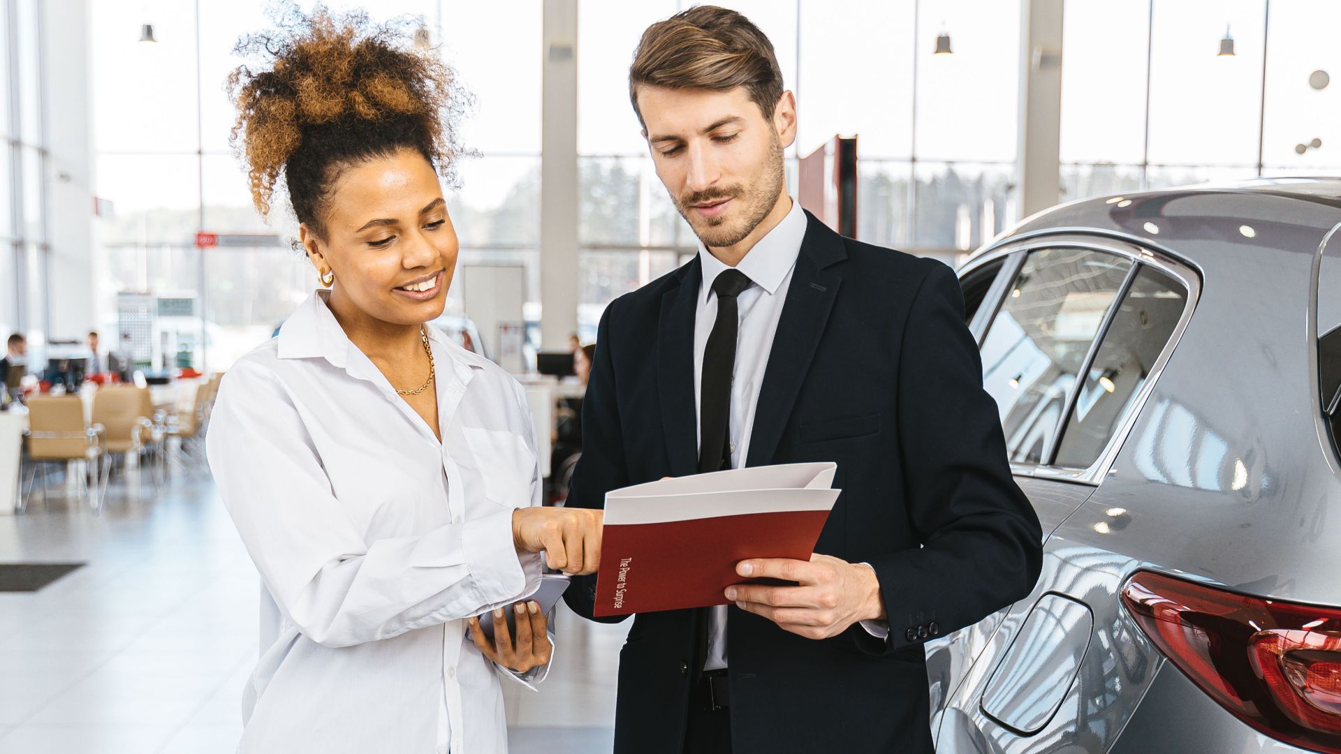 Man and woman discussing car purchase inside a modern dealership.