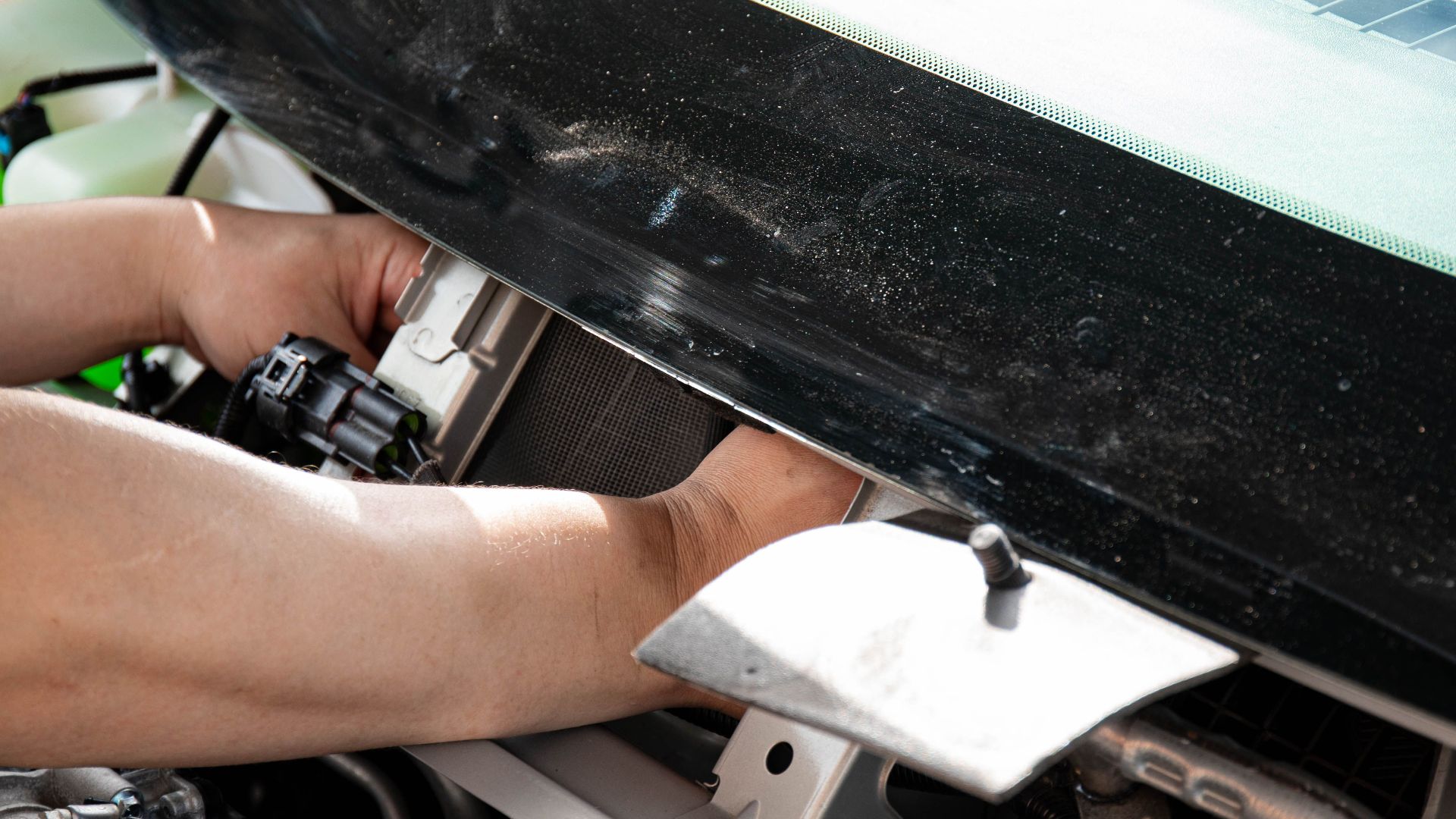 Close-up of mechanic's hands repairing a windshield wiper on a car.