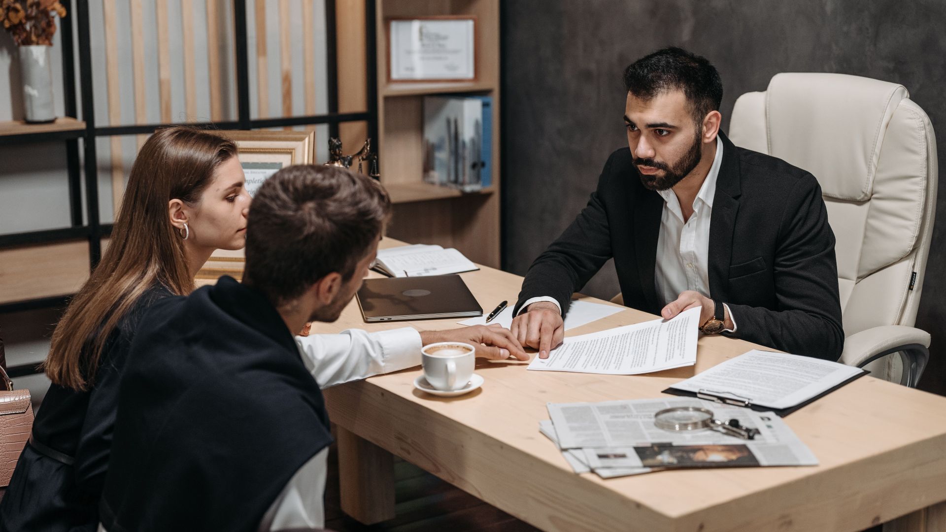 Lawyer discussing legal documents with clients at office desk.
