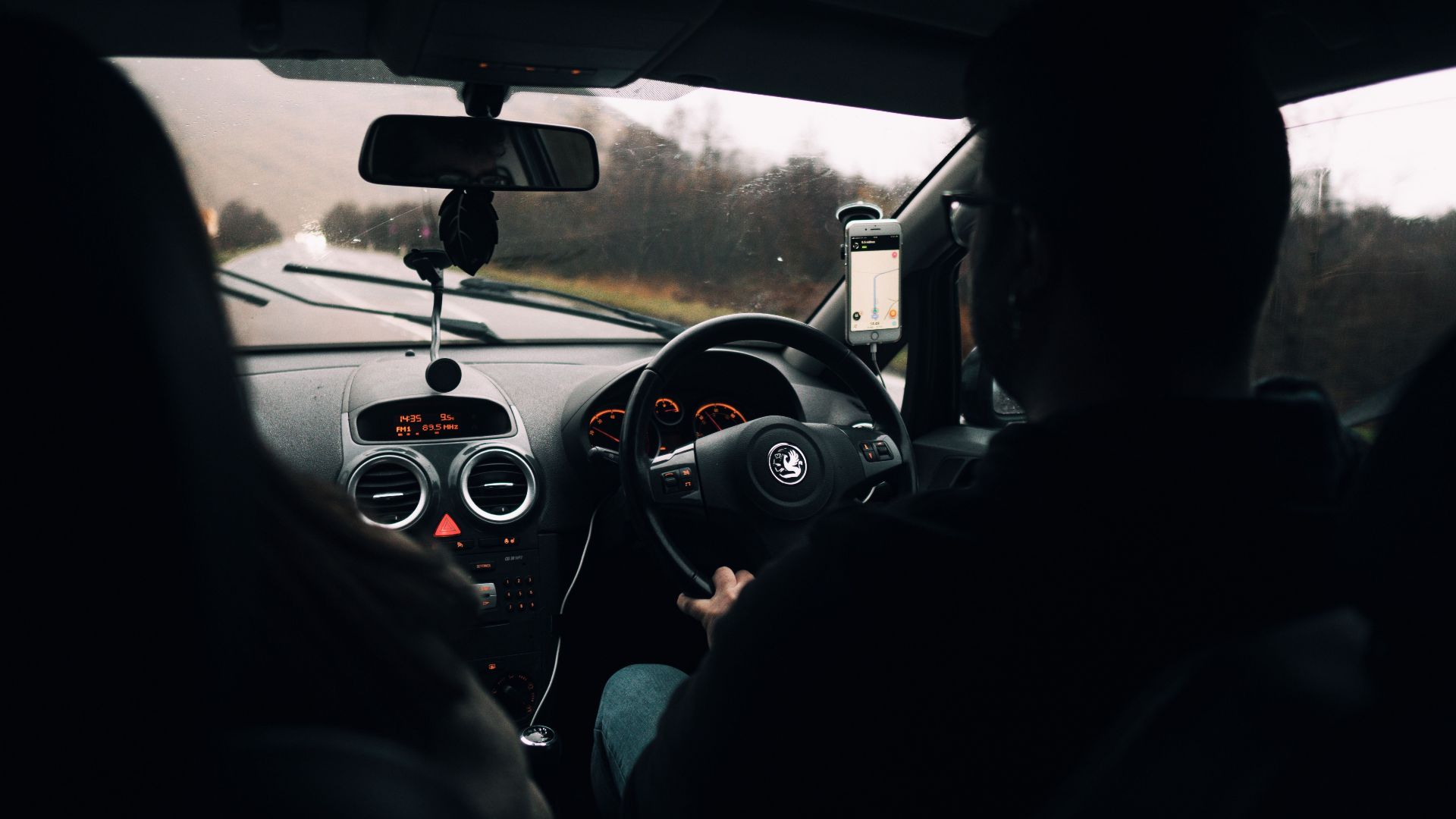 Couple driving through scenic Scottish countryside on a rainy day, inside car view.