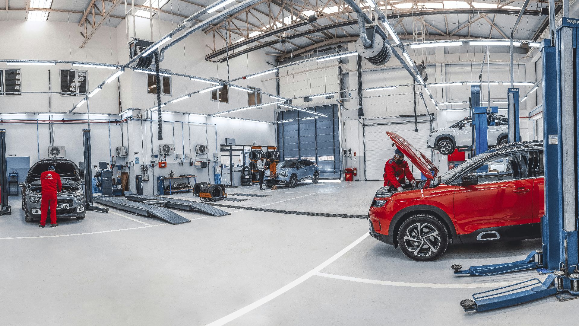 Mechanics working on cars in a bright, spacious automotive repair workshop