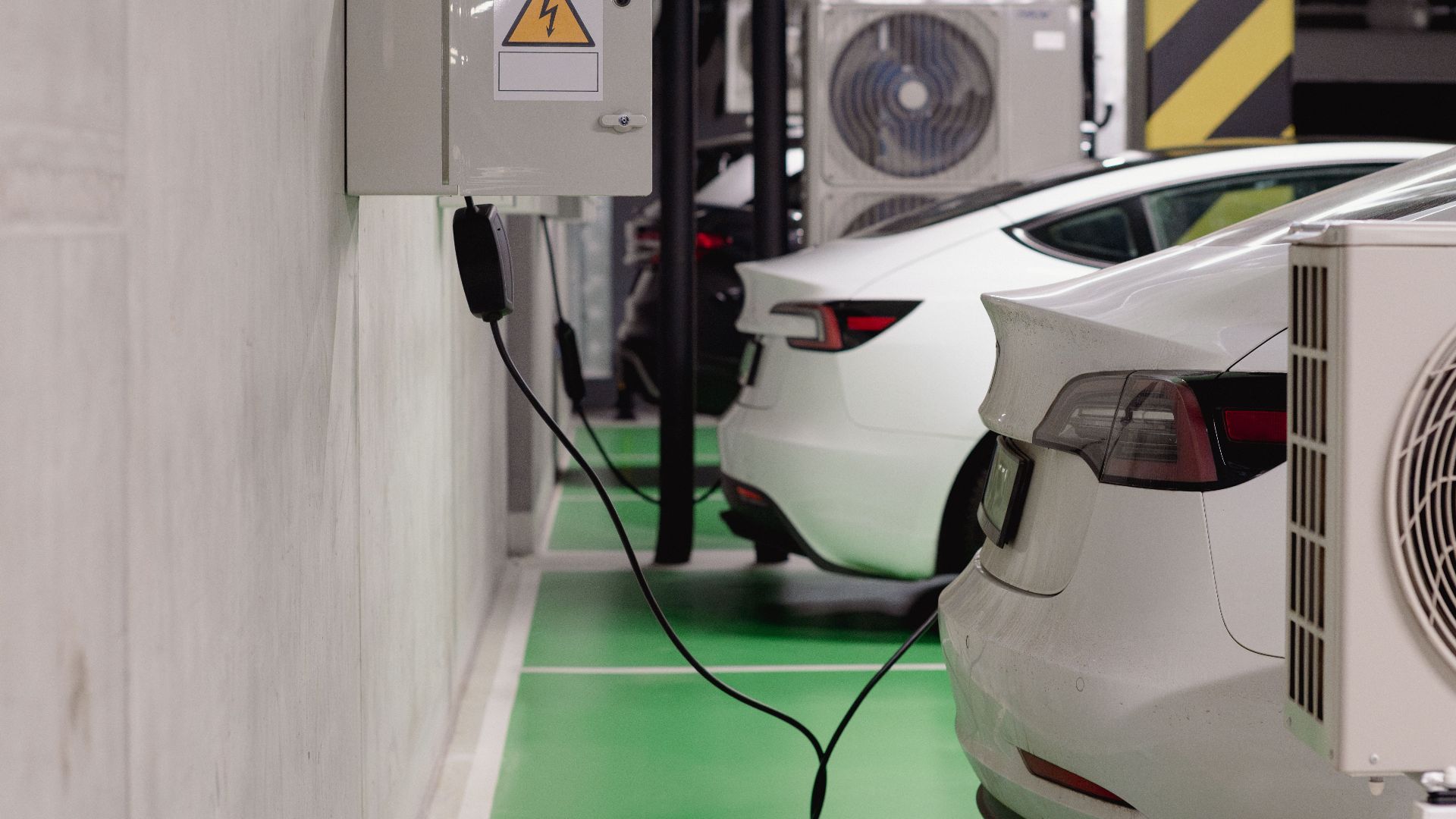 Electric vehicles charging at an indoor station in a modern underground garage.