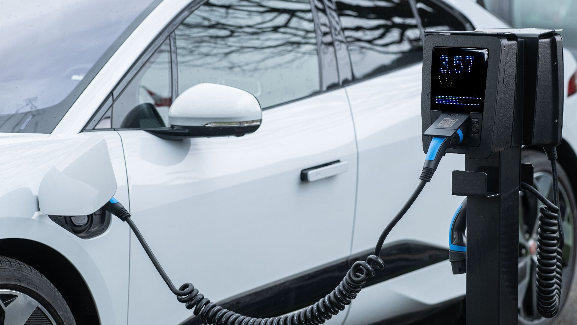 Close-up of an electric vehicle charging at a station, showcasing energy-efficient technology.