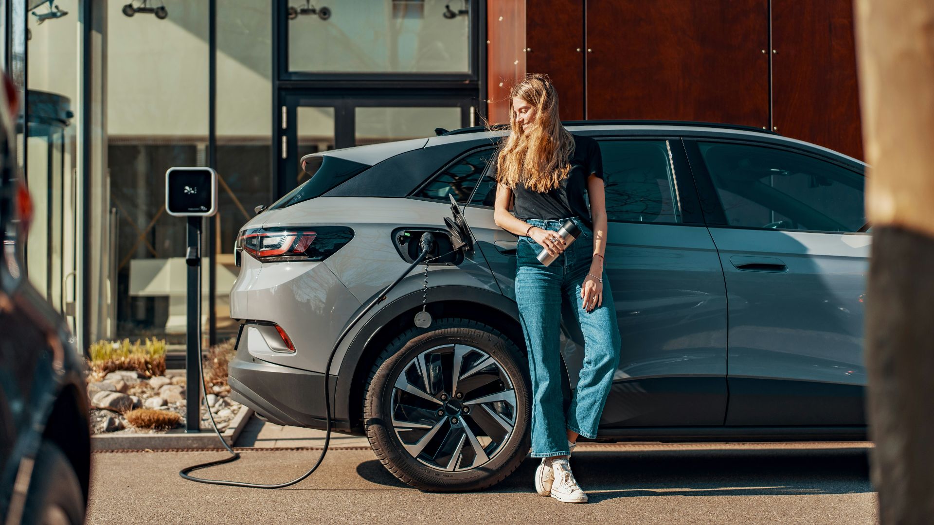 a woman standing next to a blue car
