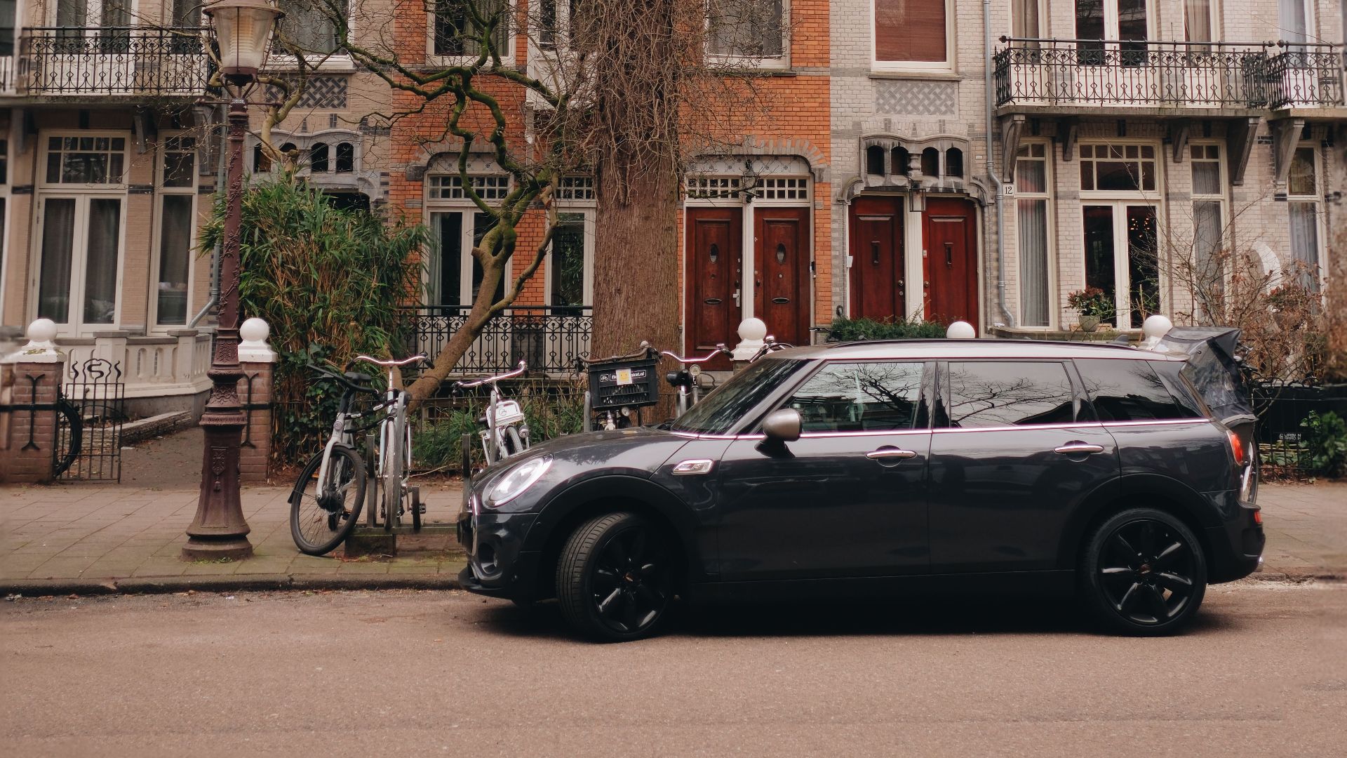 Parked black Mini Cooper in front of charming Dutch townhouses in an urban street setting.