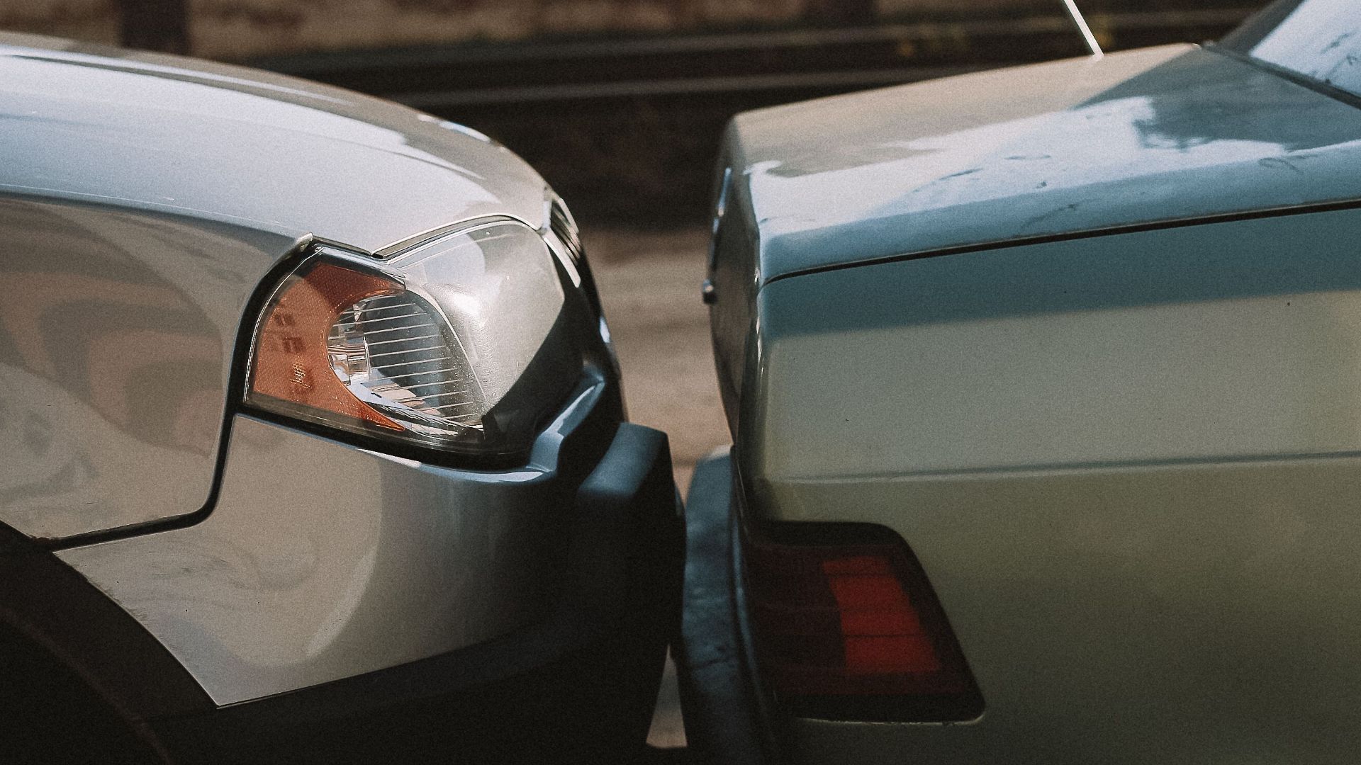 A close-up view showing the aftermath of a rear-end car collision in an outdoor setting.