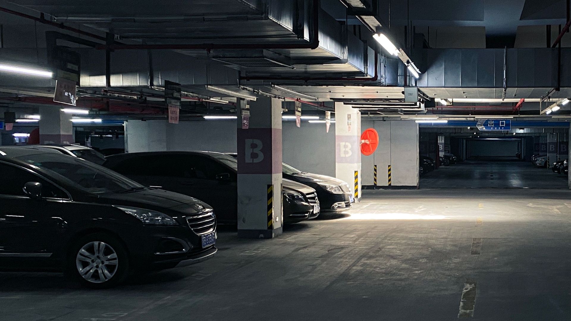 A dark underground parking garage with parked cars and minimal lighting in Wuxi, Jiangsu.