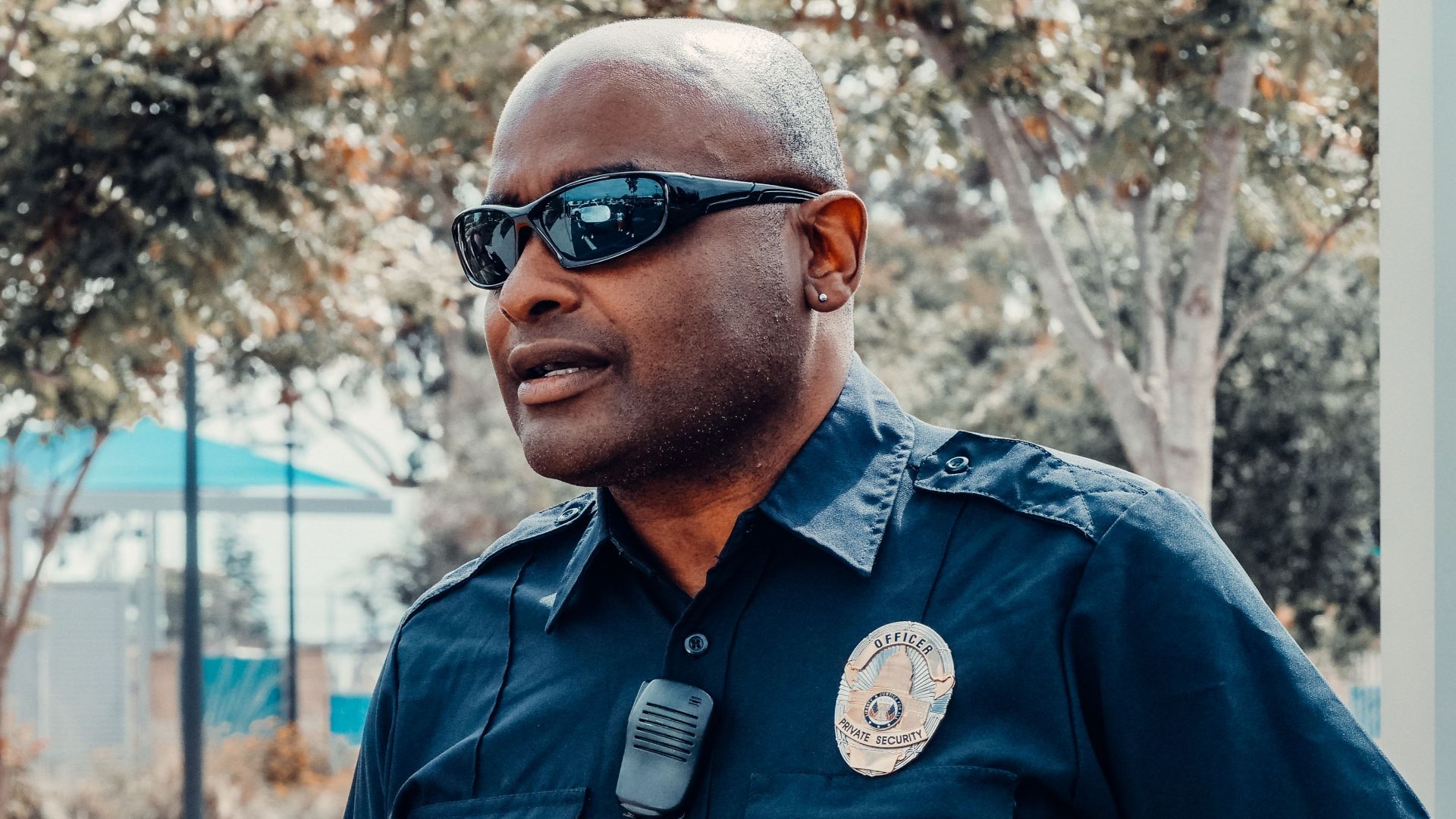 A police officer in uniform standing outdoors, holding a radio, and ensuring public safety.