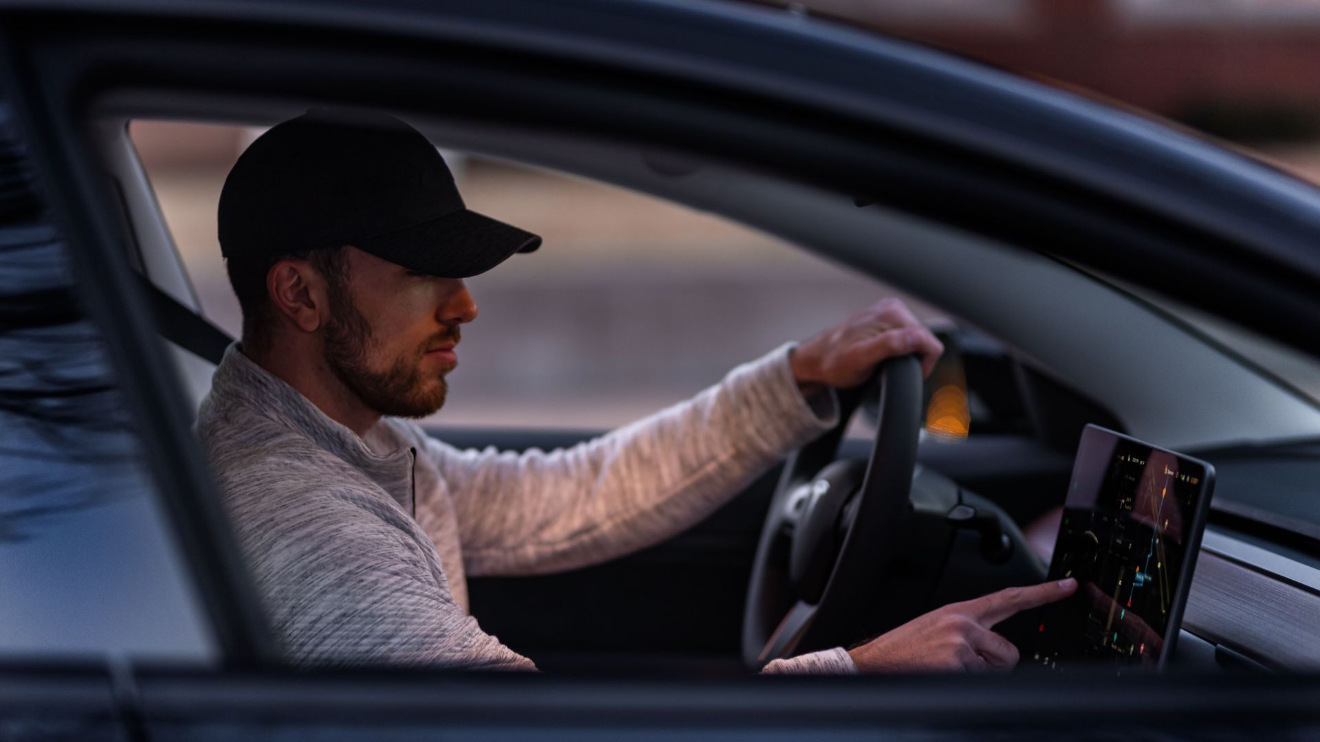 A man interacts with a touchscreen inside an electric car, driving through Dallas, TX.
