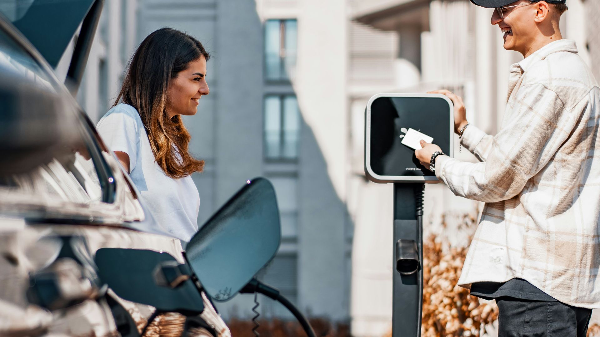 a man and a woman are charging their cars