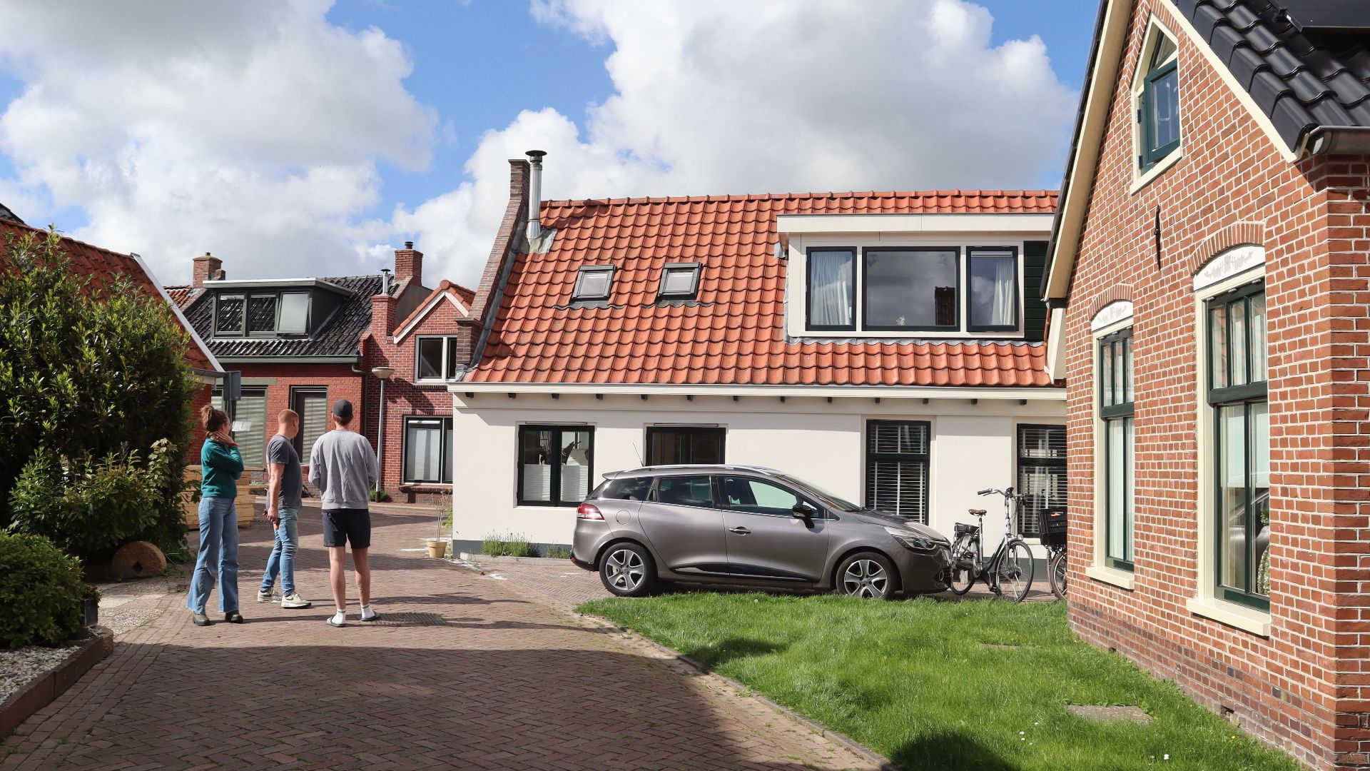 Charming view of traditional Dutch houses in Winsum, Netherlands with people standing outdoors.