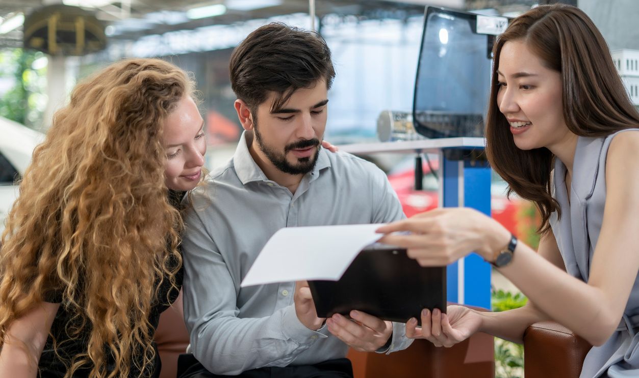 Auto business, car sale, consumerism and people concept - woman Sign Contract with car dealer in auto show. car salesman is making deal with lender. Used cars cheaper than new cars. But to buy a used