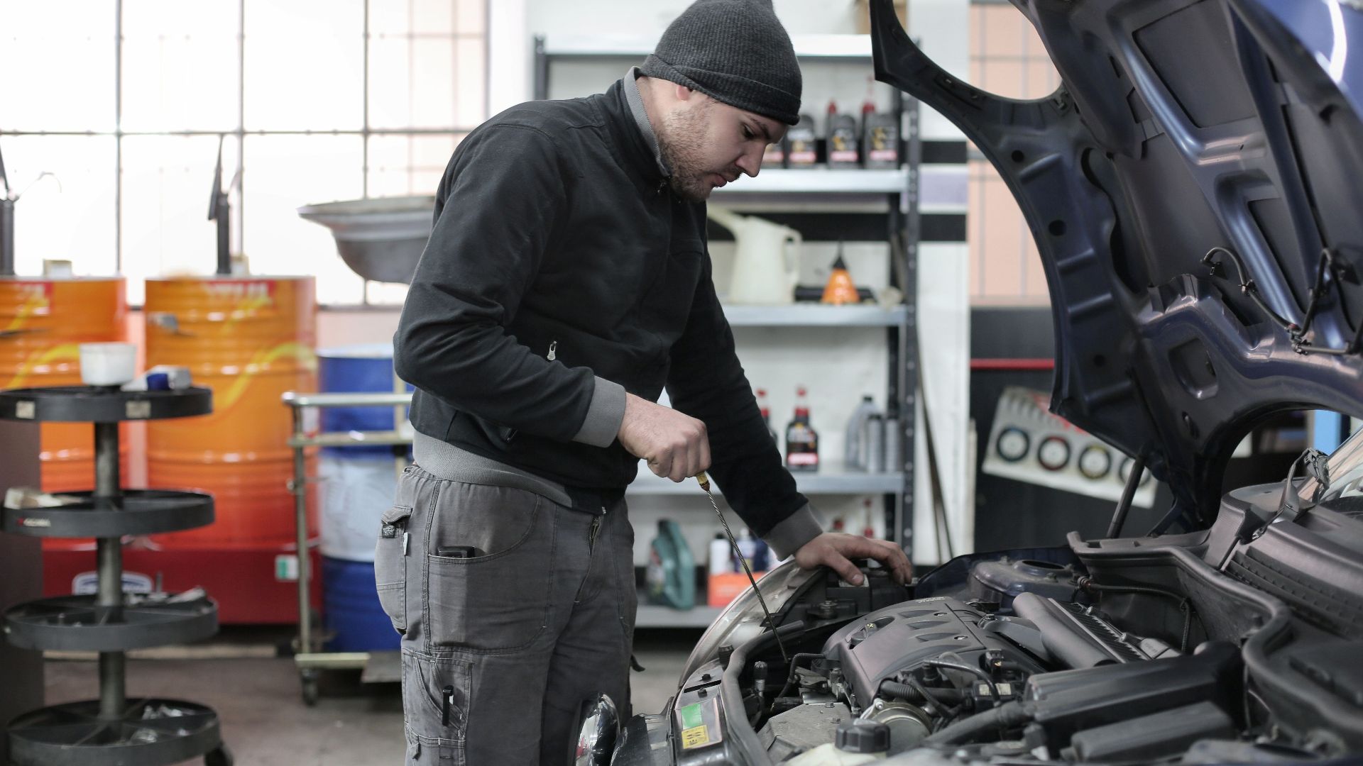 Mechanic checking a car engine in a garage, ensuring quality maintenance and repair.