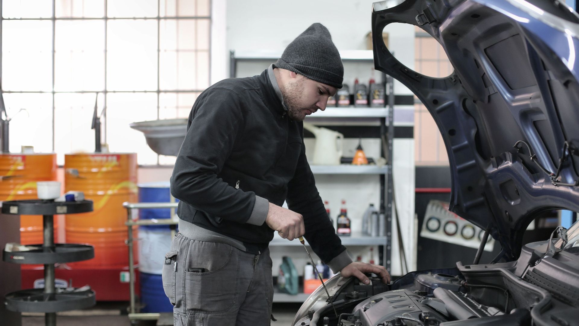 Mechanic checking a car engine in a garage, ensuring quality maintenance and repair.