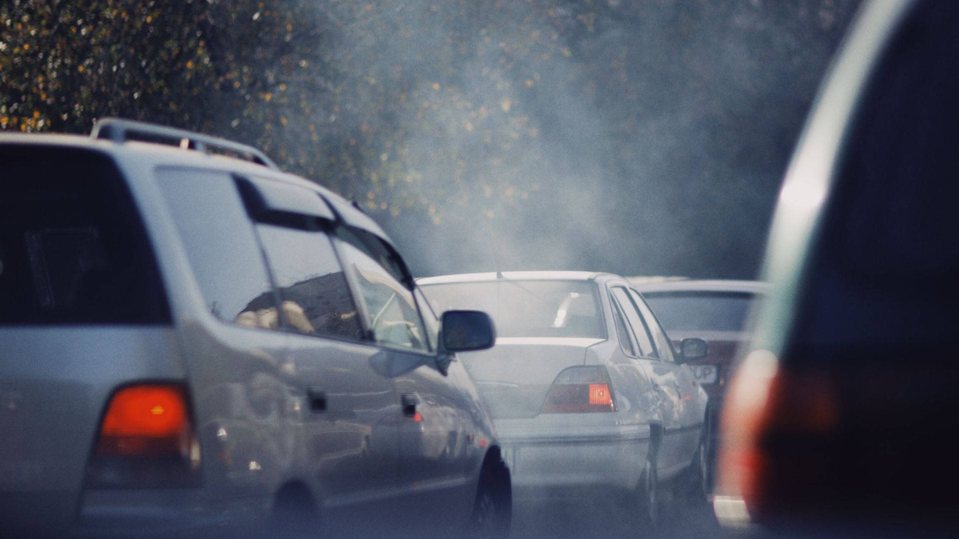 City traffic jam with cars emitting smoke on a busy road.