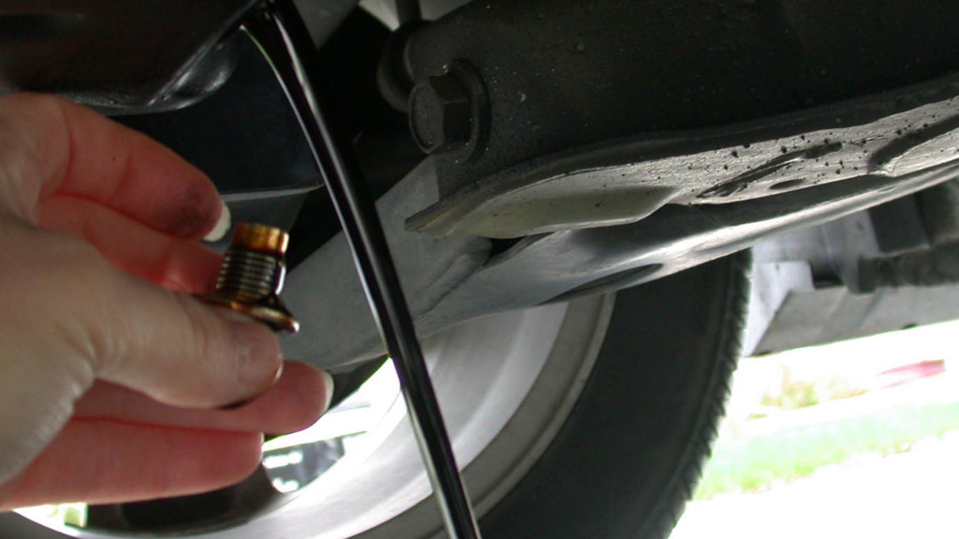 Draining the motor oil out of an automobile as part of an oil change.