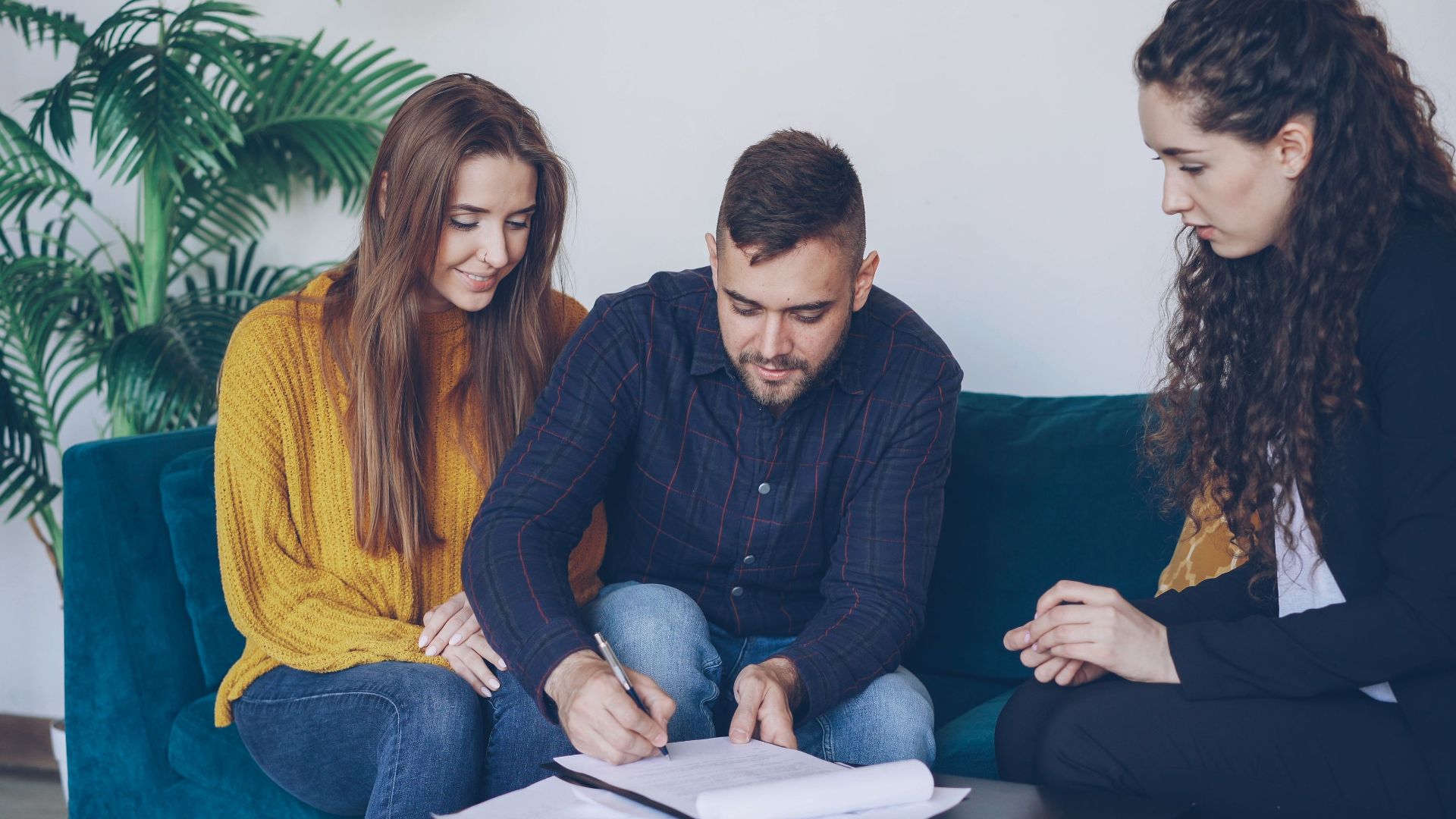 Young couple consults with financial advisor, signing important documents indoors.