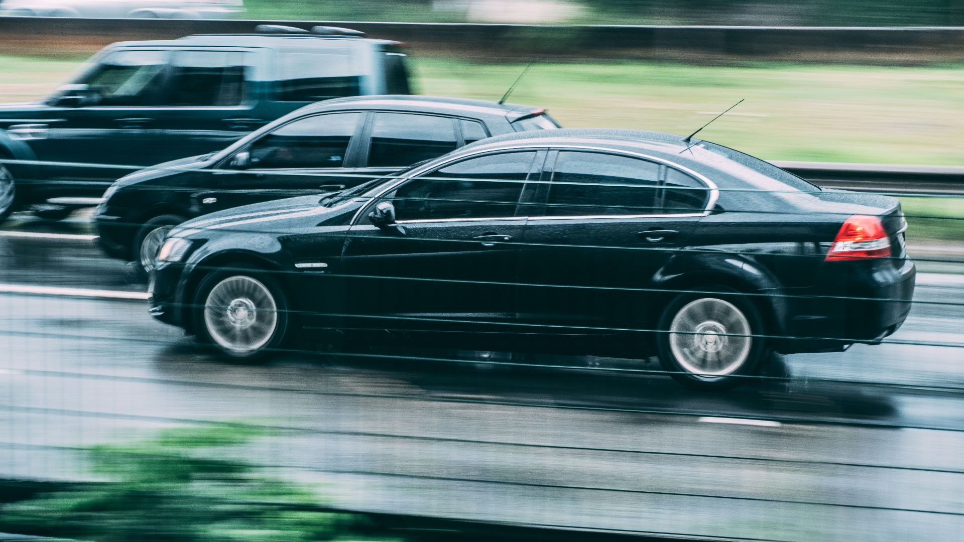 Blurred image of two cars racing on a wet highway, highlighting speed and motion.