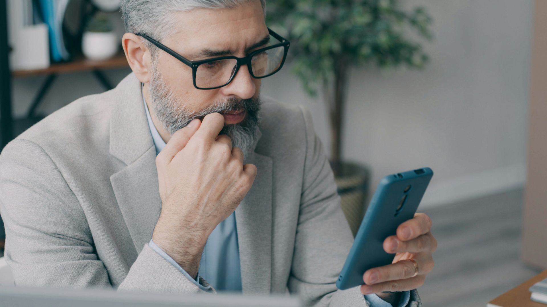 A man sitting at a desk looking at a cell phone