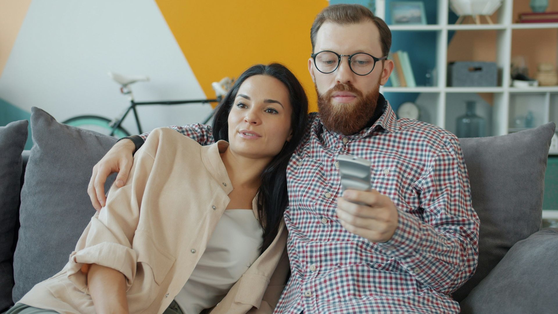 Couple sitting on couch, man holding credit card