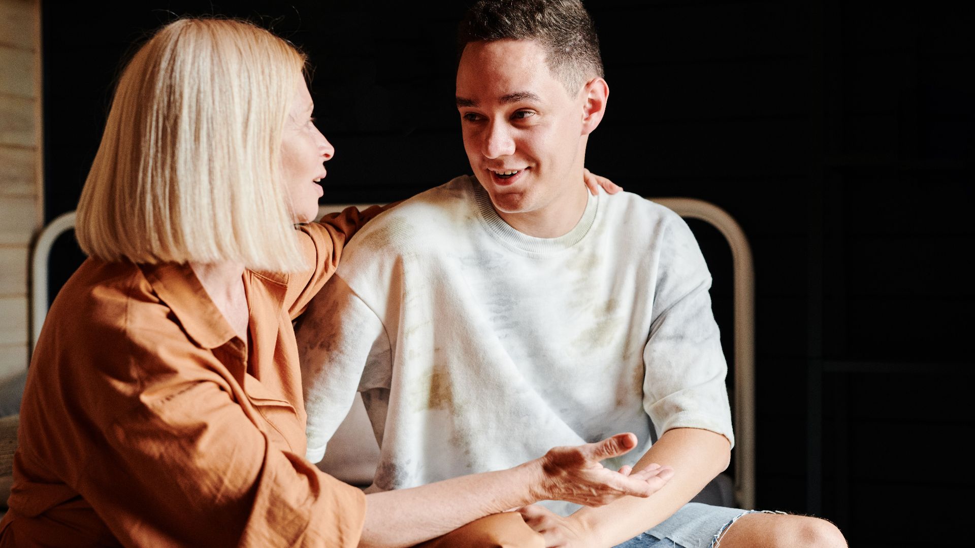 A mother and son engage in a warm, heartfelt conversation indoors.