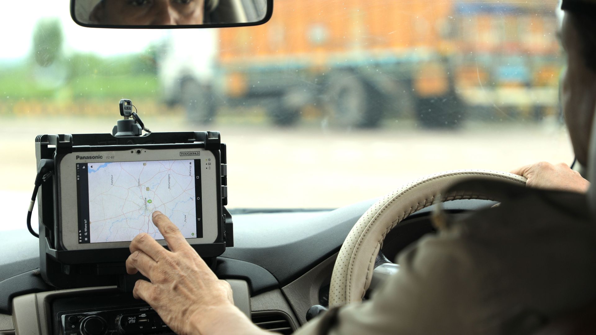 Police officer navigates using a digital map on a tablet inside a vehicle.