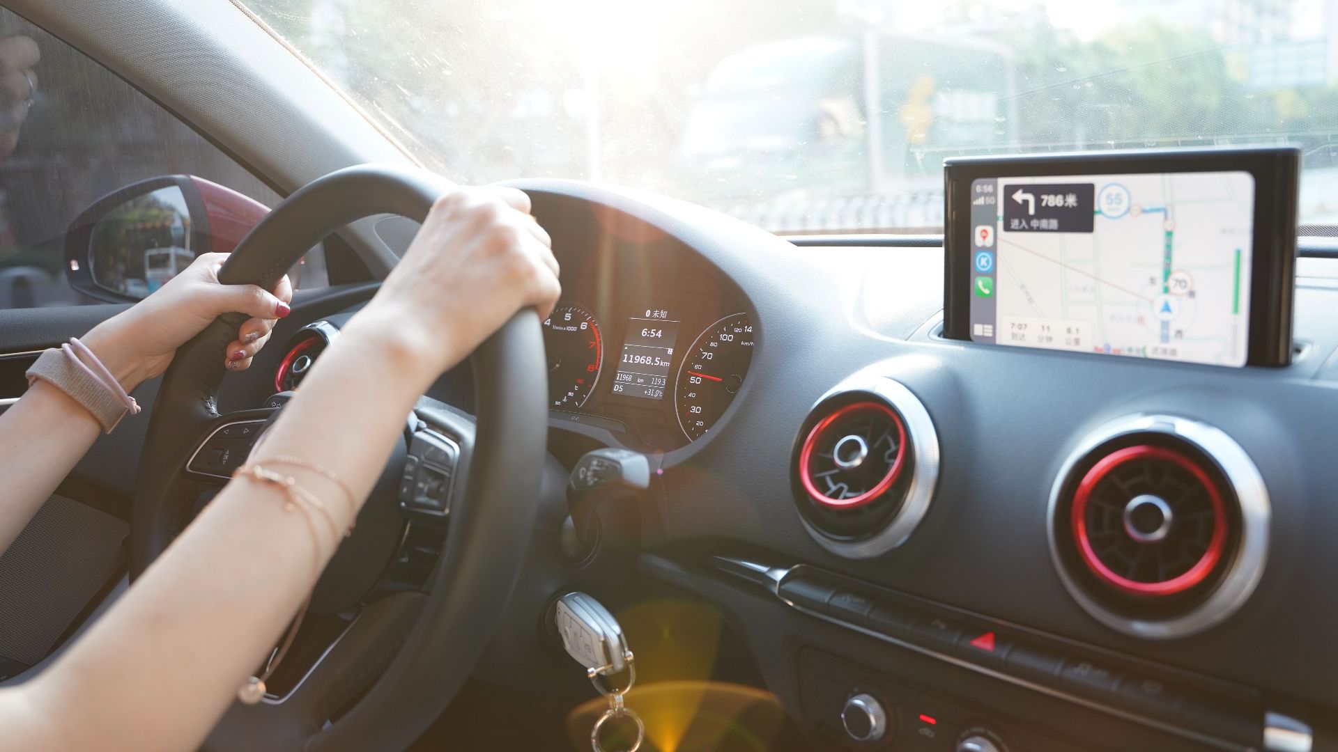 Hands on steering wheel using GPS navigation inside car during road trip.