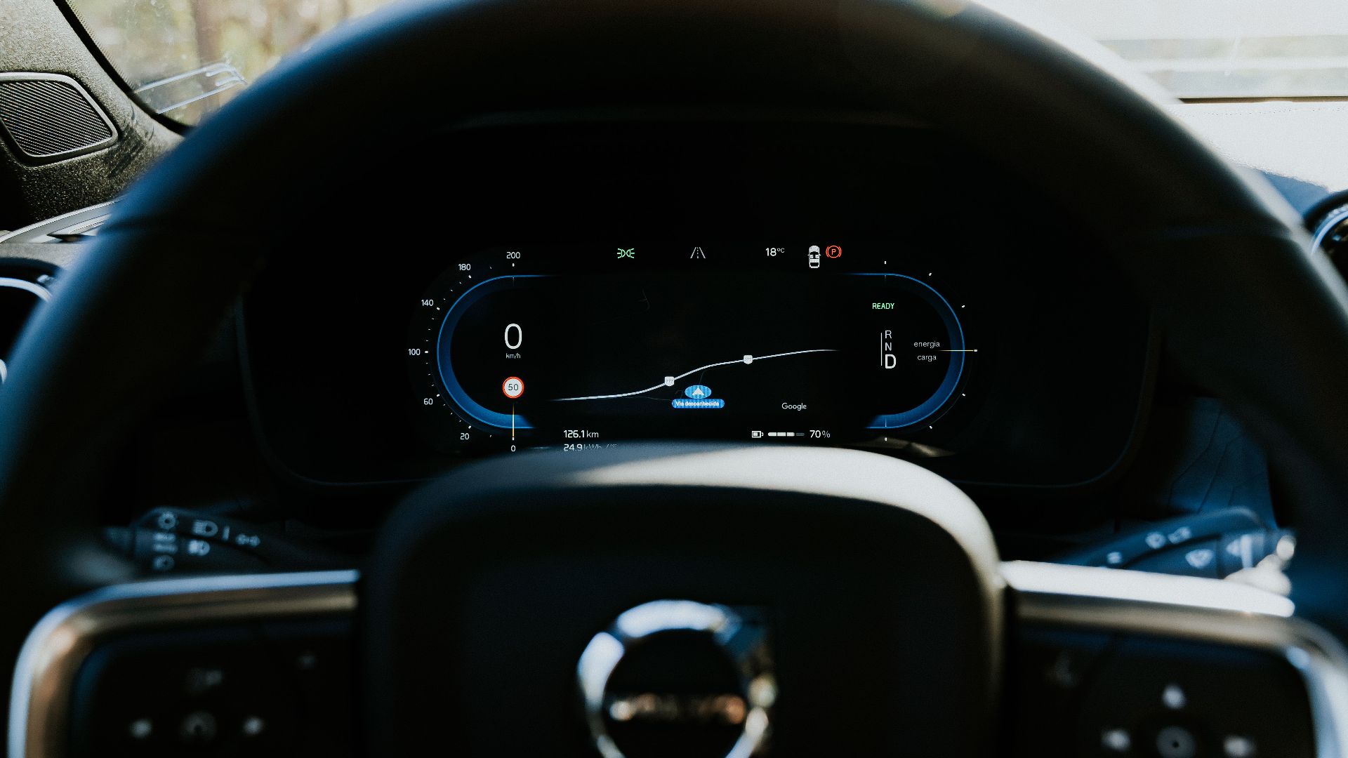 Close-up of a Volvo car steering wheel with digital dashboard display, showcasing modern automotive technology.