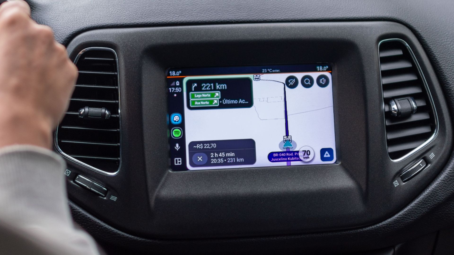 View of GPS navigation screen inside a moving car with driver on the road.