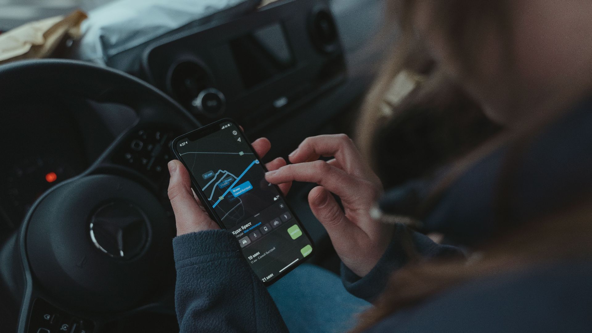 Person using GPS navigation app on smartphone inside car for directions.