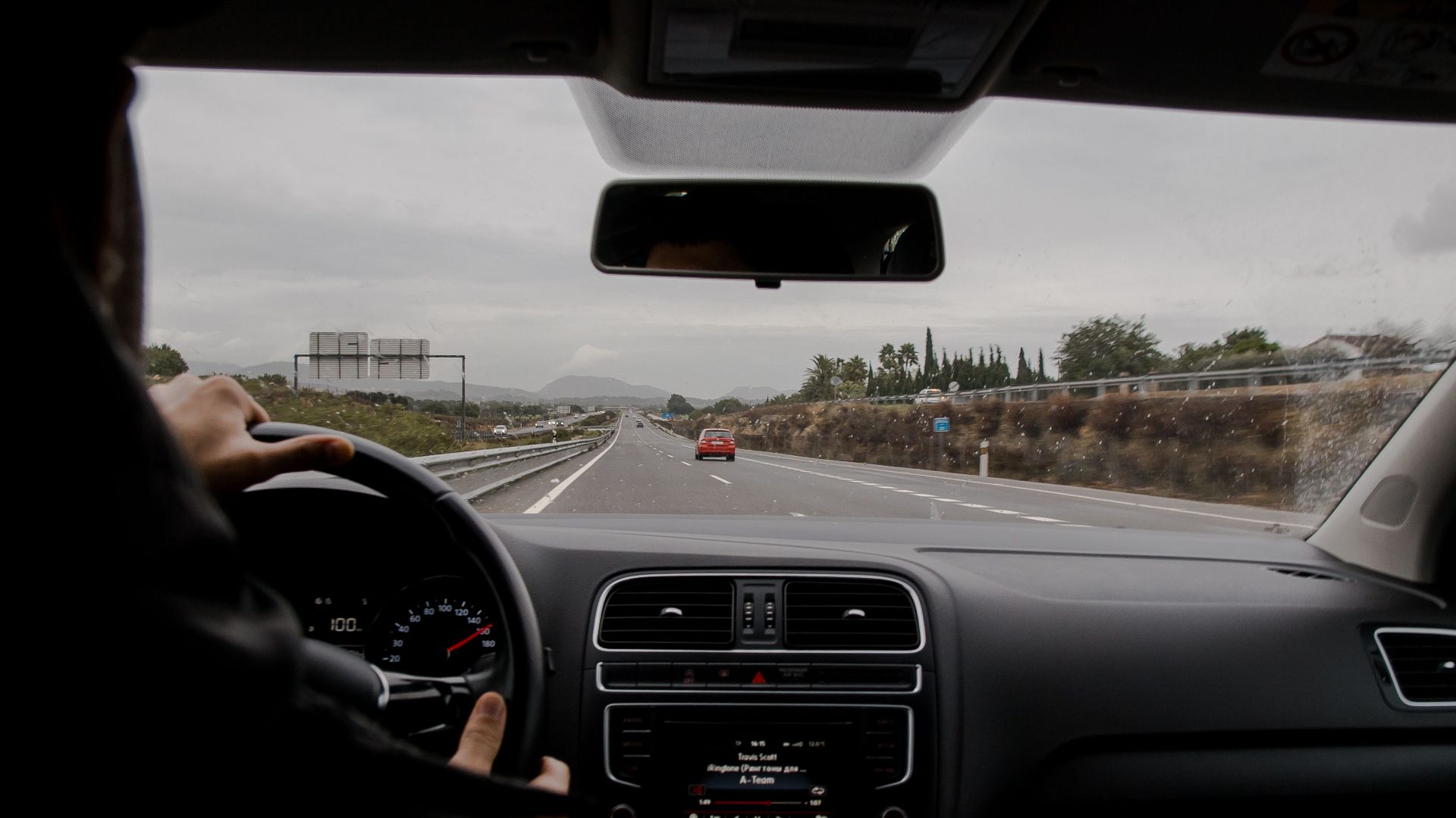 Anonymous man driving fast along asphalt road on modern vehicle in overcast weather
