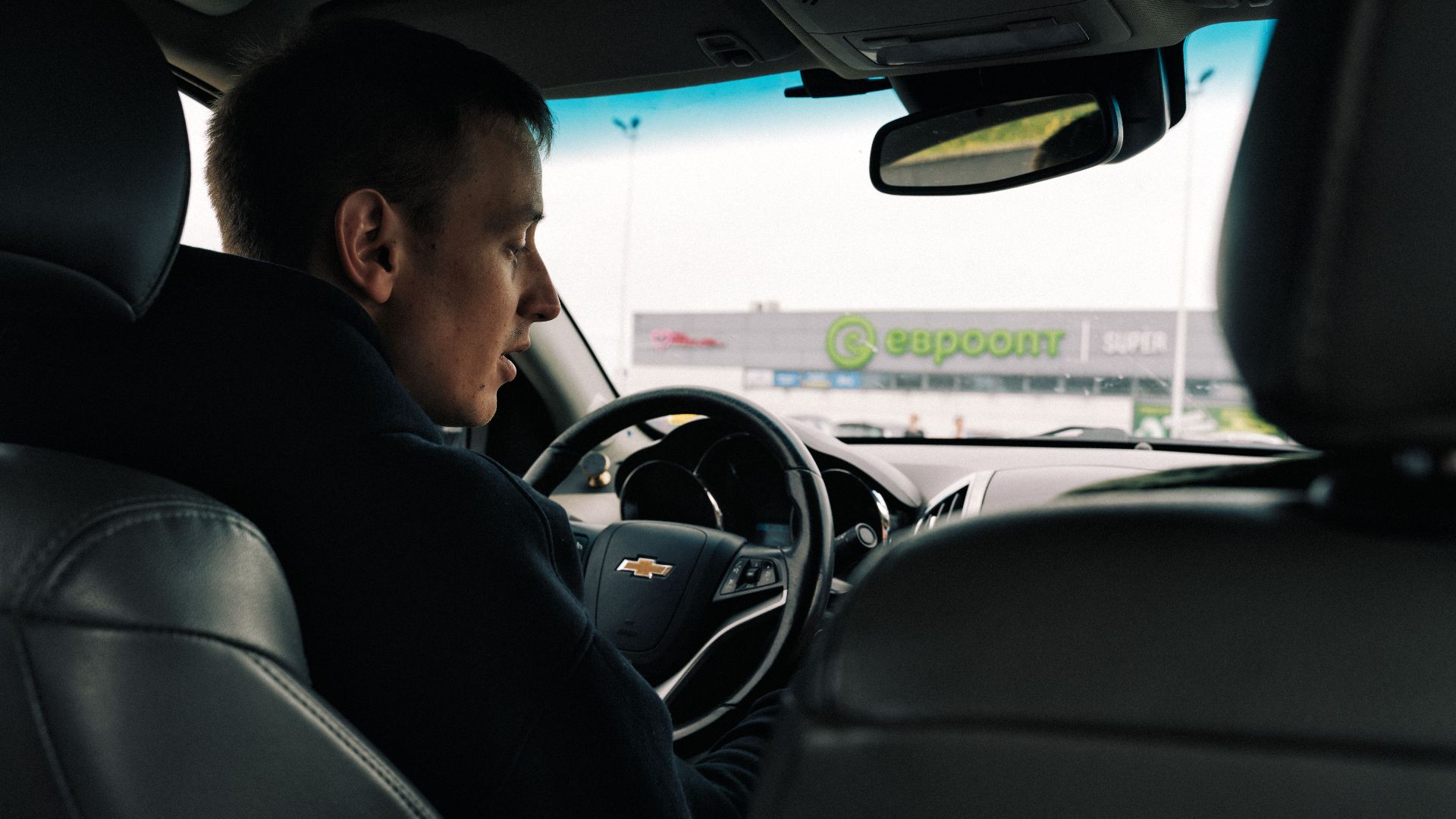 View from inside a car with a driver against a backdrop of a shopping center in Novoyelnya, Belarus.