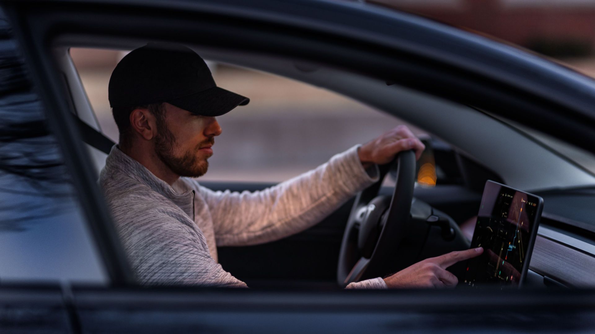 A man interacts with a touchscreen inside an electric car, driving through Dallas, TX.