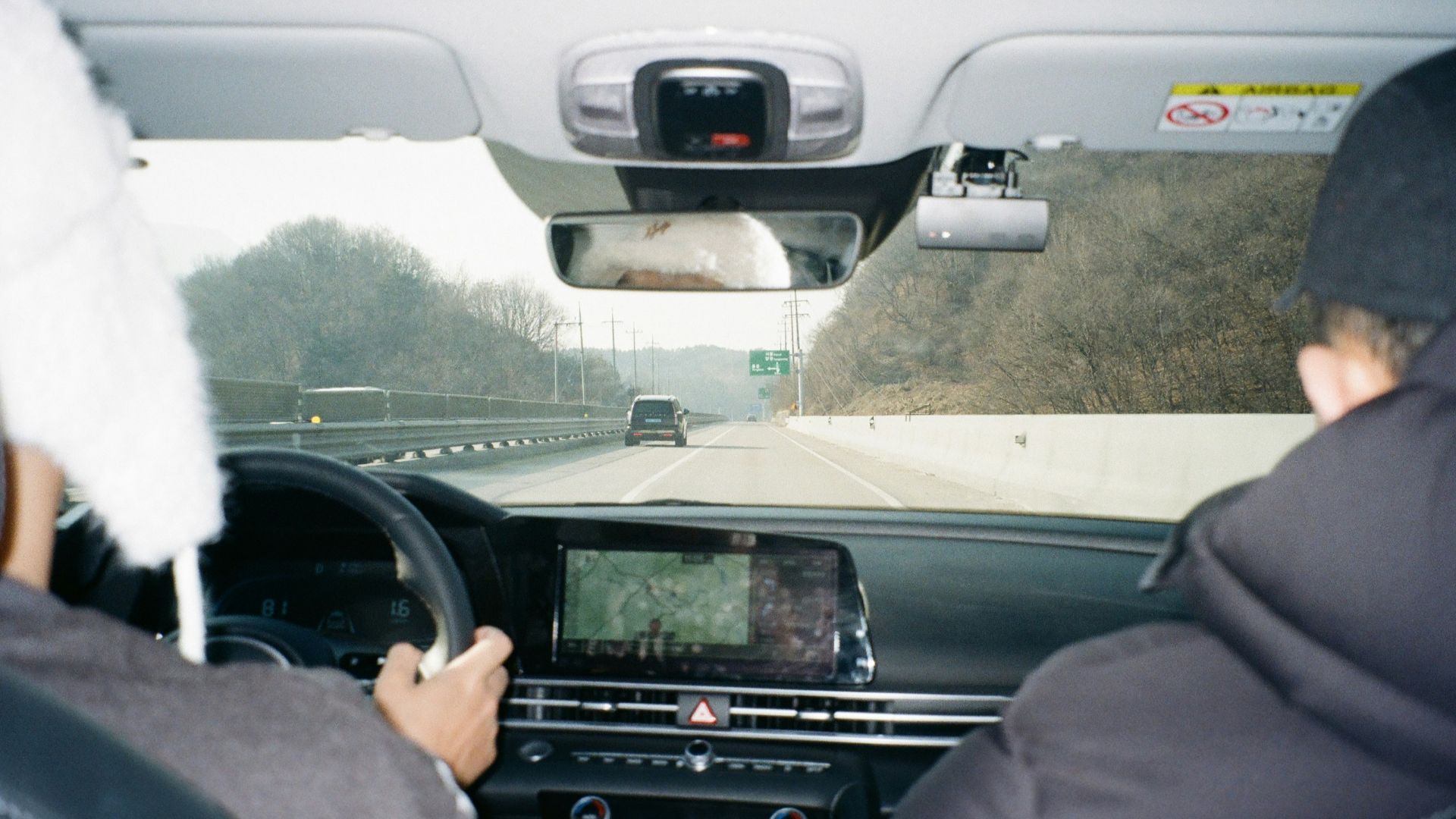 Two people driving a car on a highway