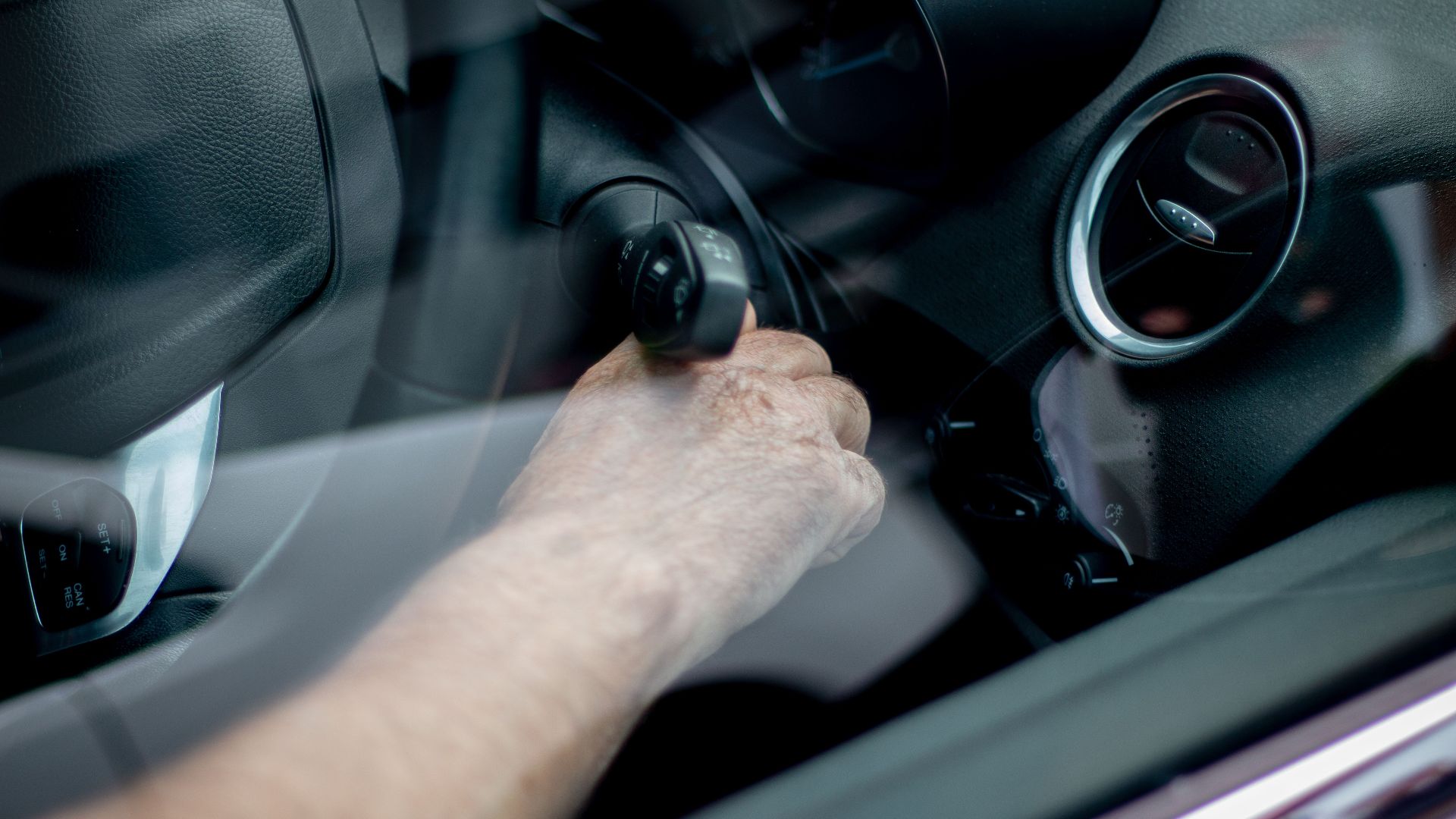 Close-up of a driver's hand starting the car ignition in Leeds, UK.