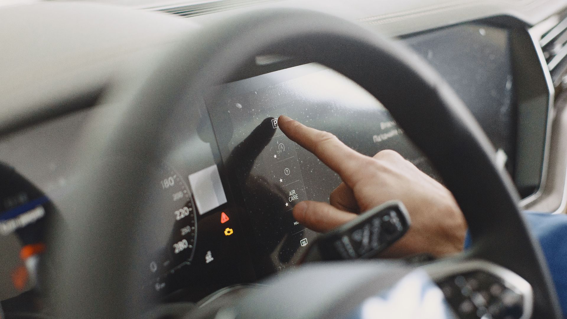 Close-up of a hand interacting with a car's digital dashboard. Modern technology and driving interface.