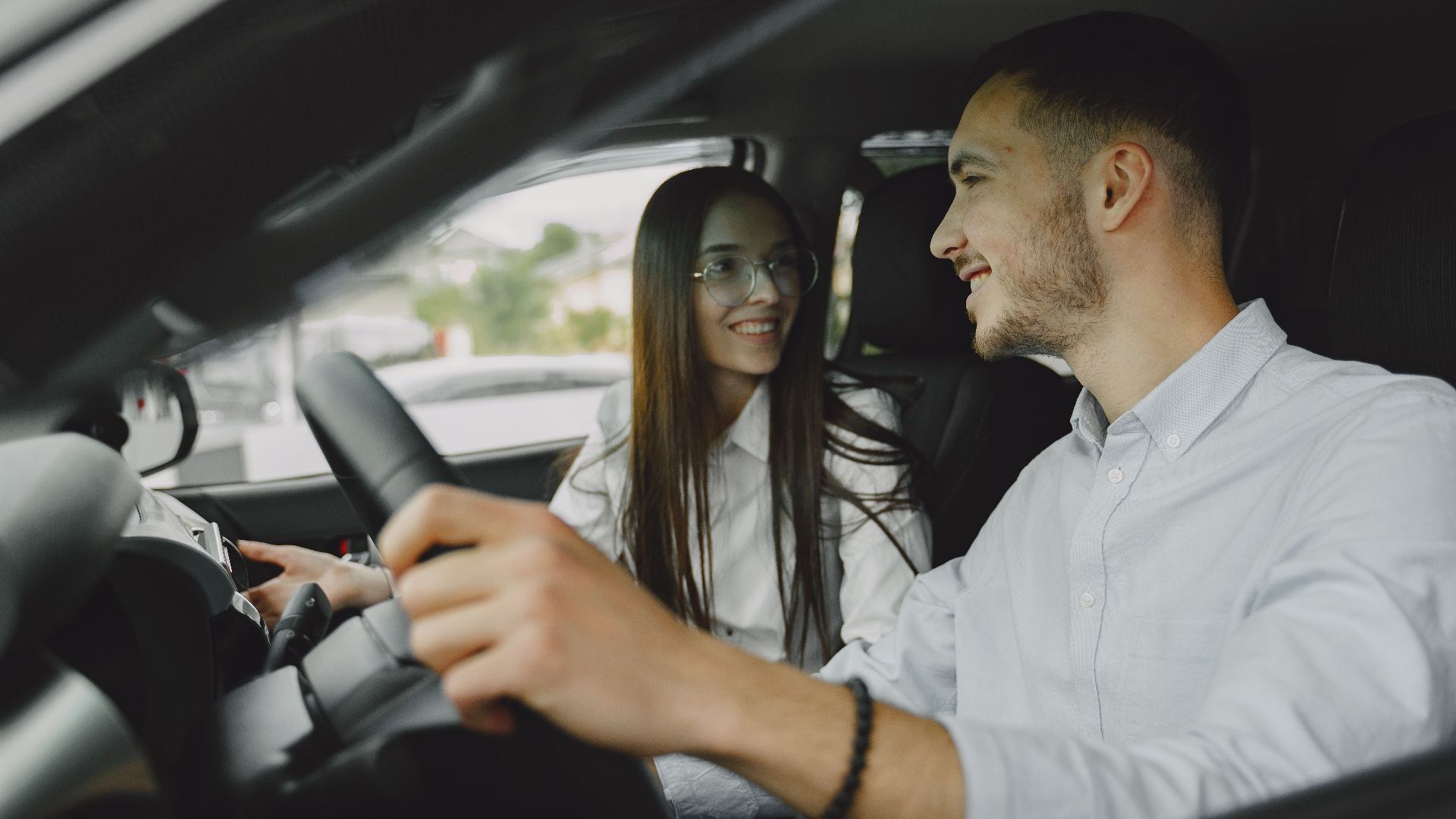 A smiling couple driving together in a car, enjoying their time on the road.