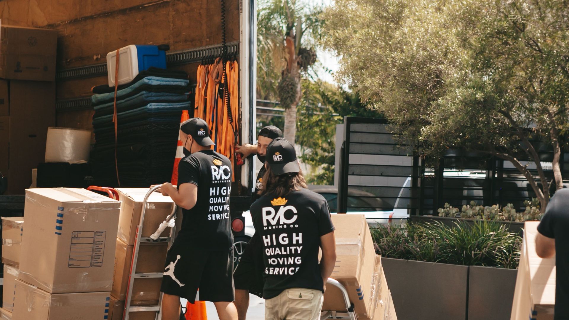 Movers loading boxes into a truck on a sunny day, capturing a busy urban scene.