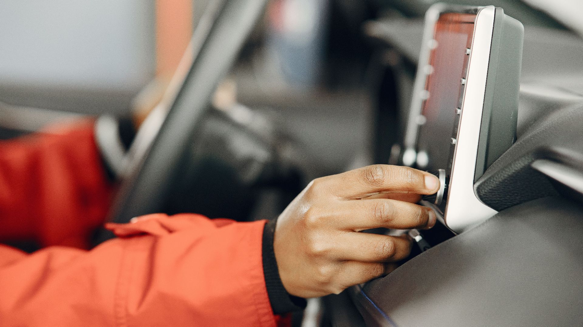 Close-up of a hand adjusting the car stereo while driving, highlighting technology and focus.