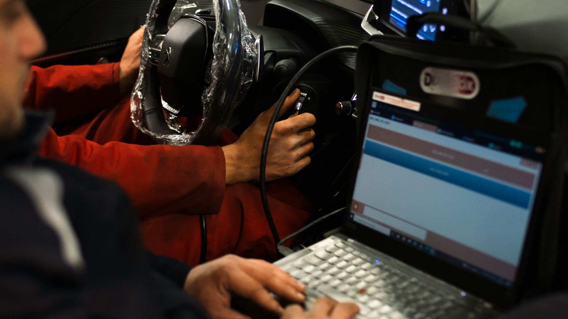 A man sitting in a car using a laptop computer