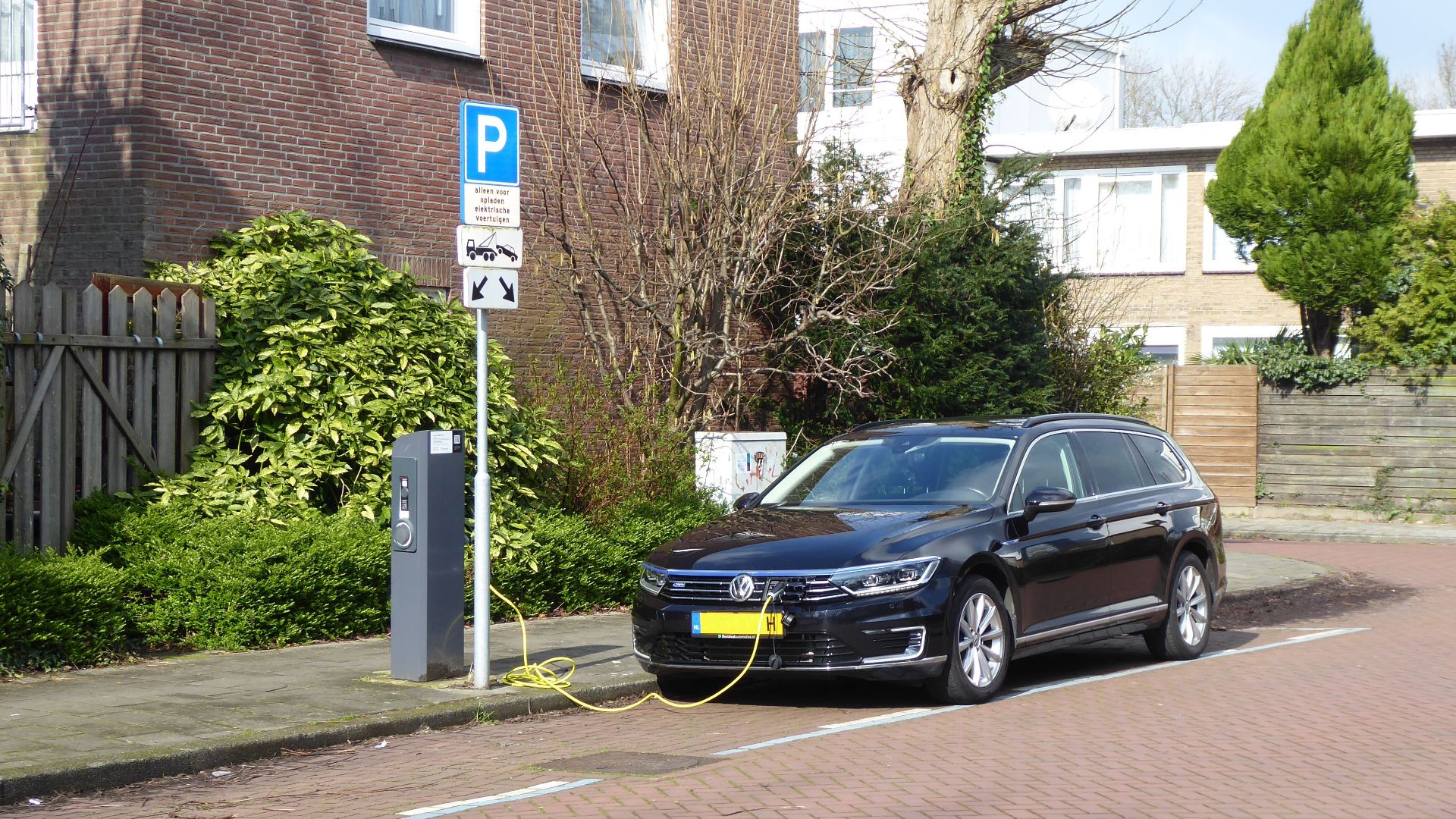 Electric car charging at a street station in Amsterdam, highlighting urban eco-friendliness.