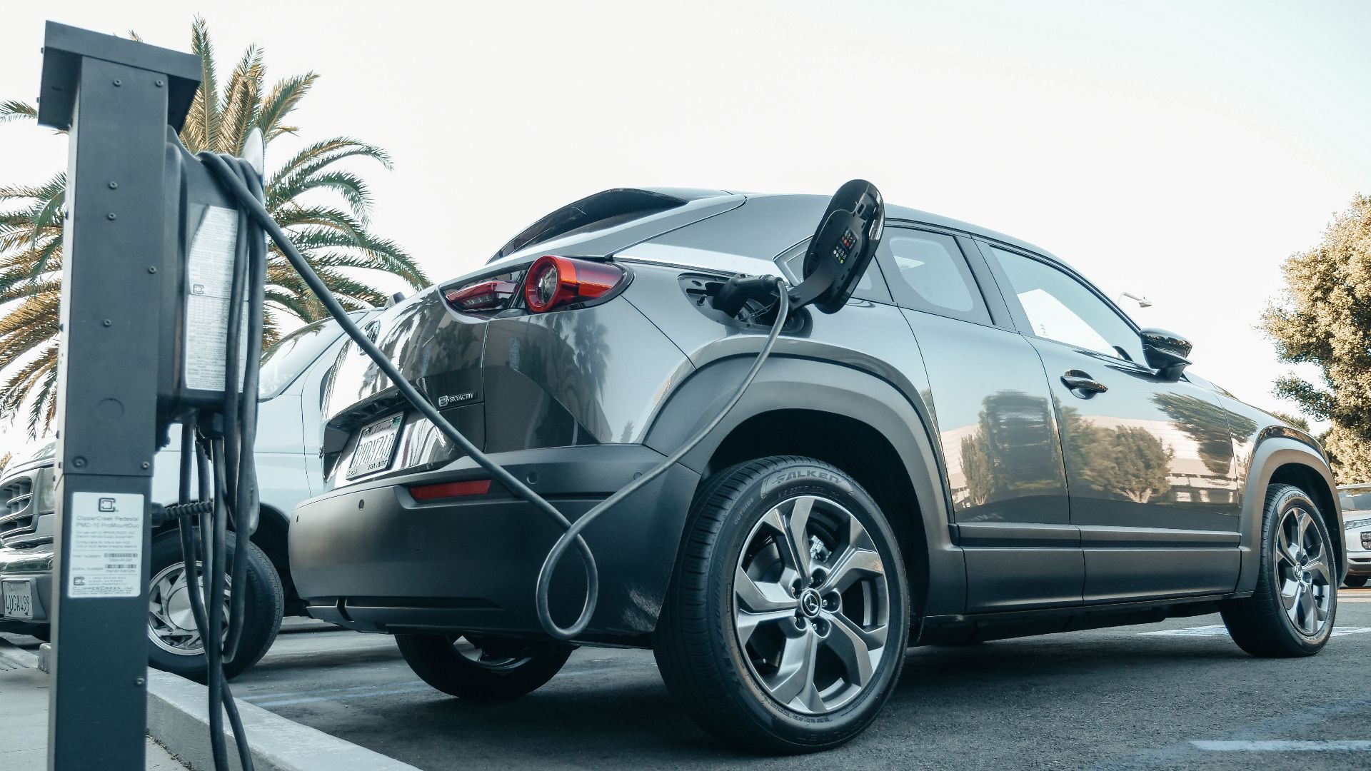 Modern electric vehicle charging at an outdoor station in daylight.