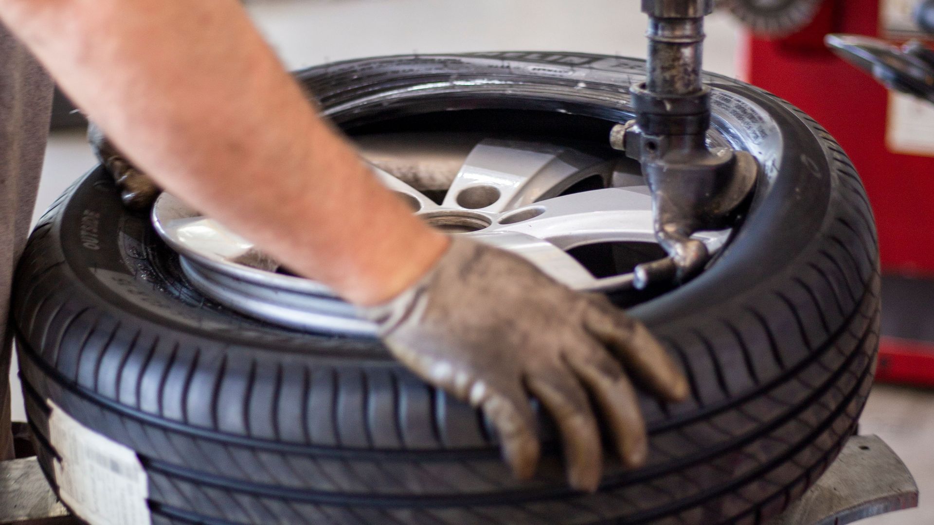 Close-up of an auto mechanic changing a tire with precision equipment in a professional workshop.