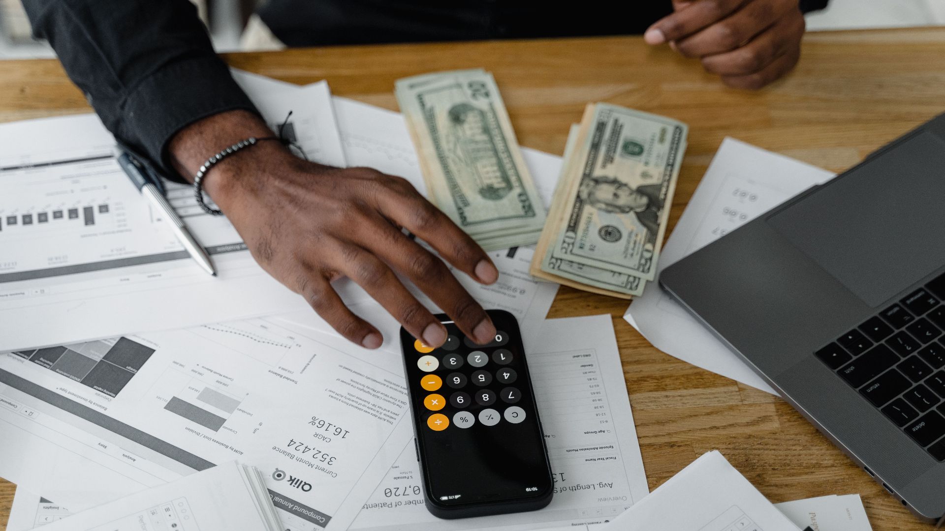 Overhead view of financial documents with calculator, cash, and laptop for financial planning.