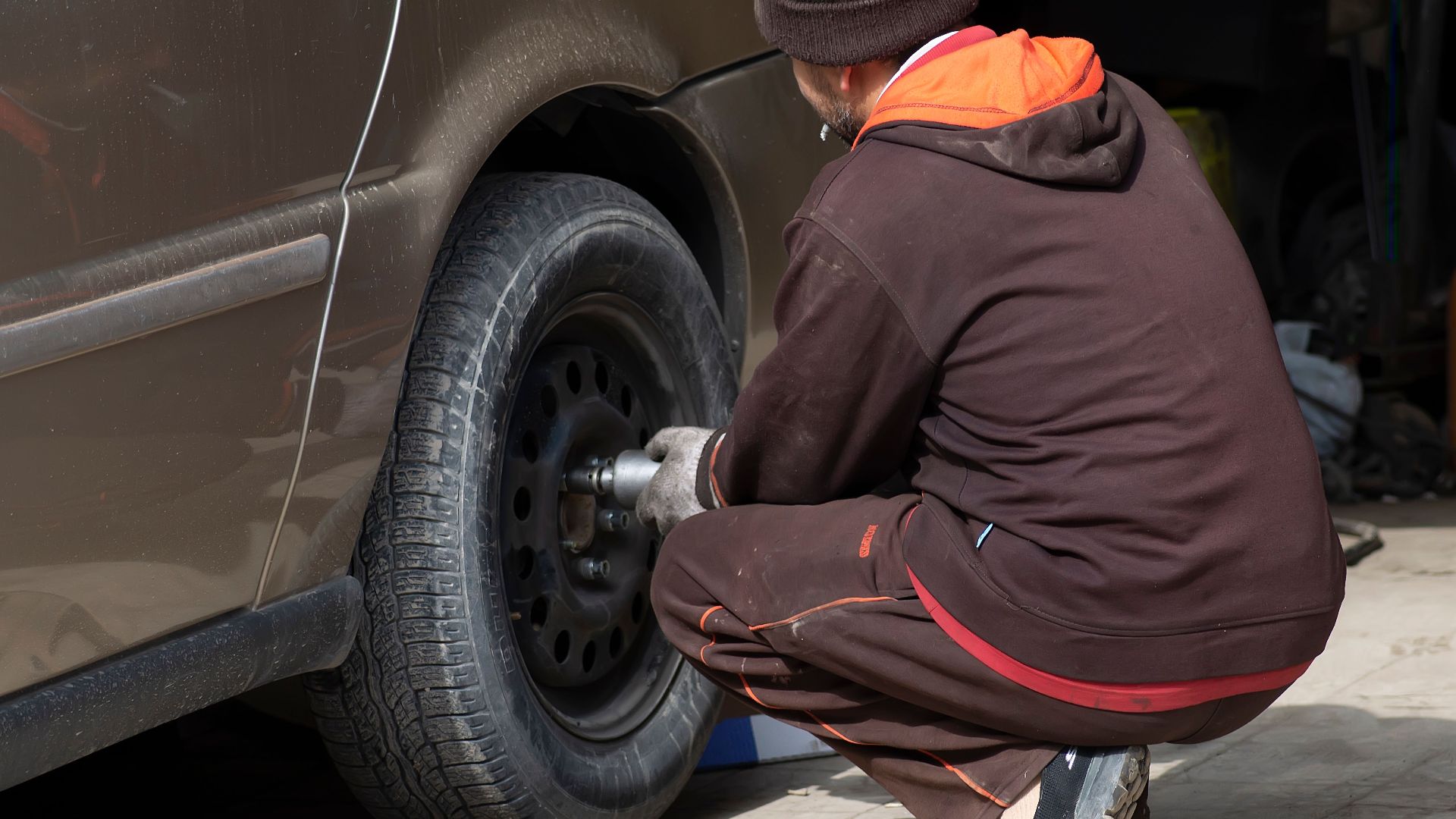 A mechanic working on a car tire, changing it in an auto repair shop.