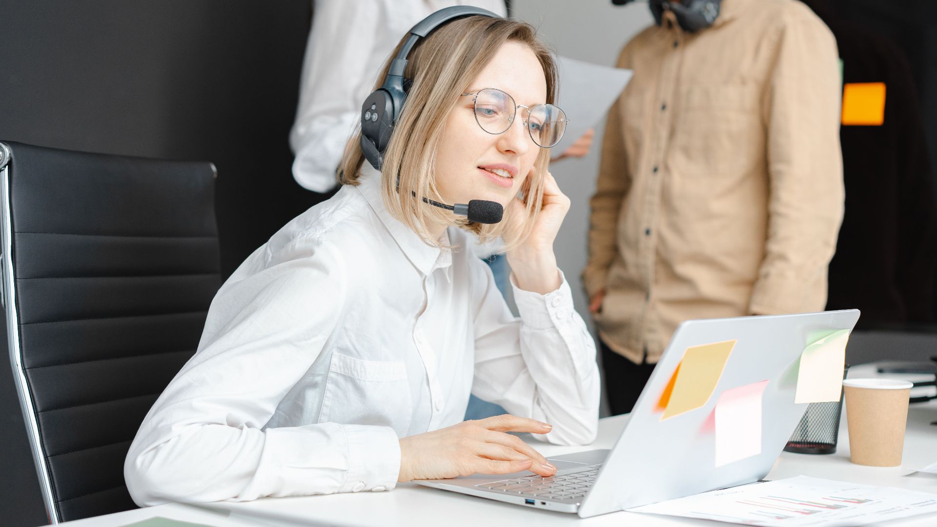 Customer support professionals working with headsets and laptops in a modern office environment.