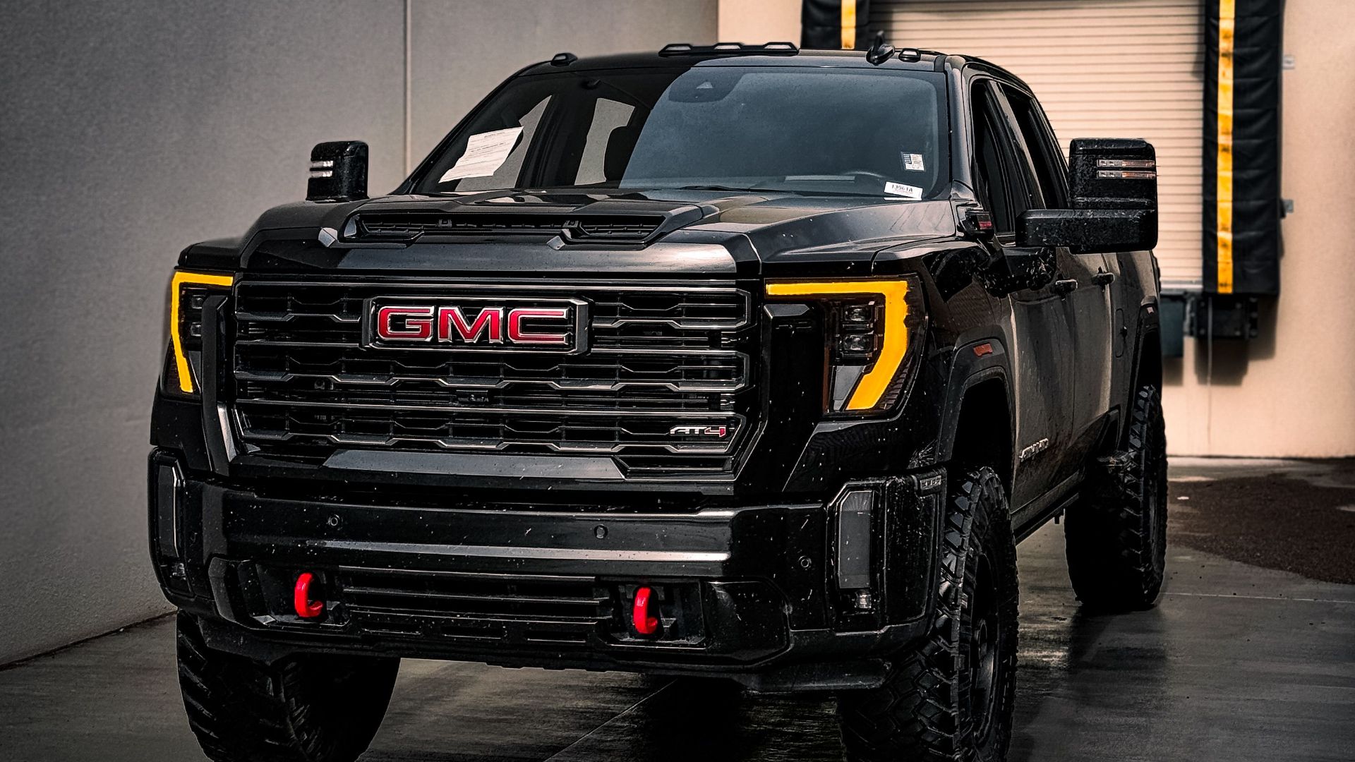 A powerful black GMC truck parked near a loading dock in an industrial area.