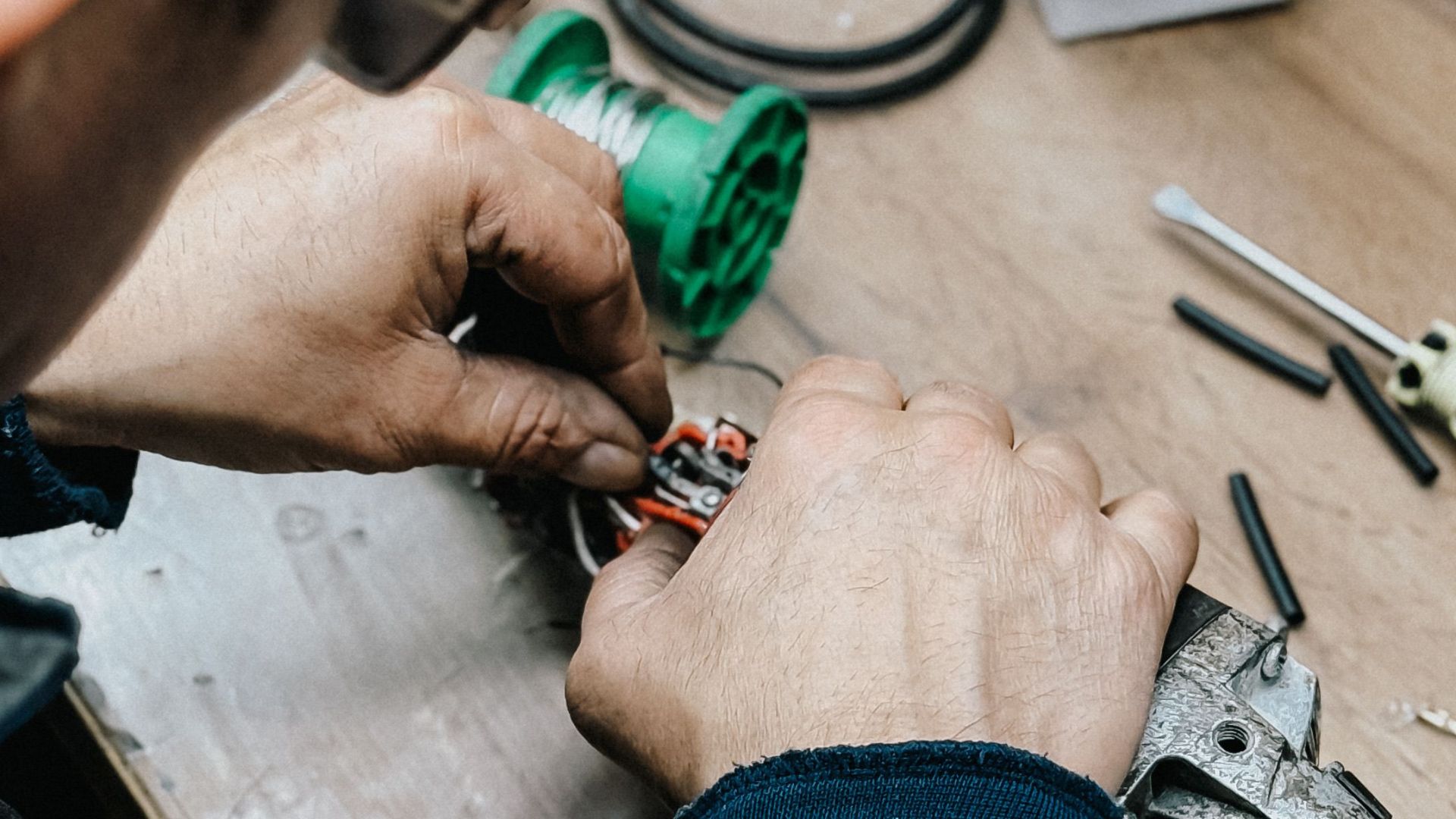 Technician working on electronic repair at a cluttered workbench.