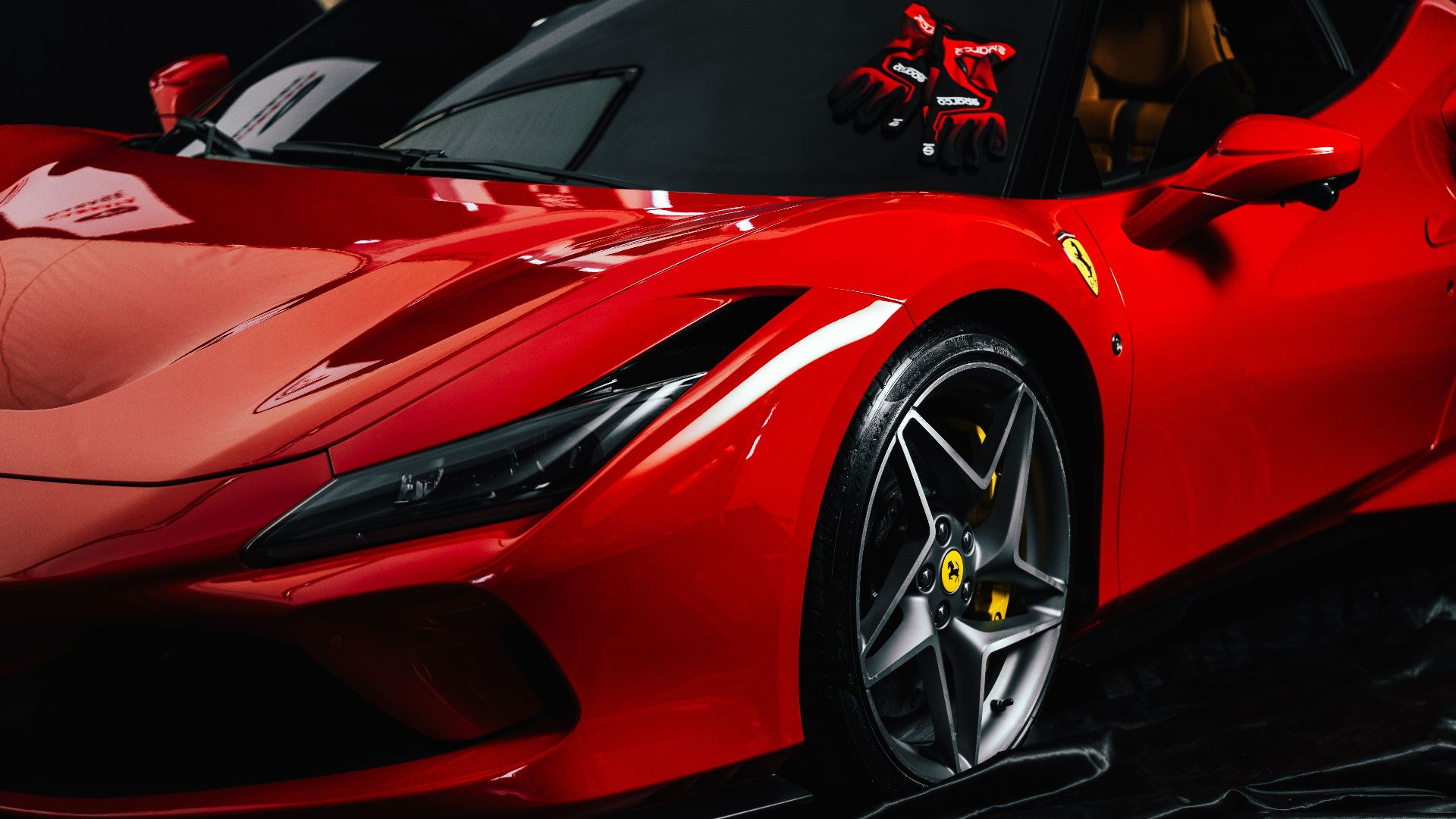 Close-up shot of a sleek red sports car with branded gloves on the dashboard. Ideal for luxury automotive themes.