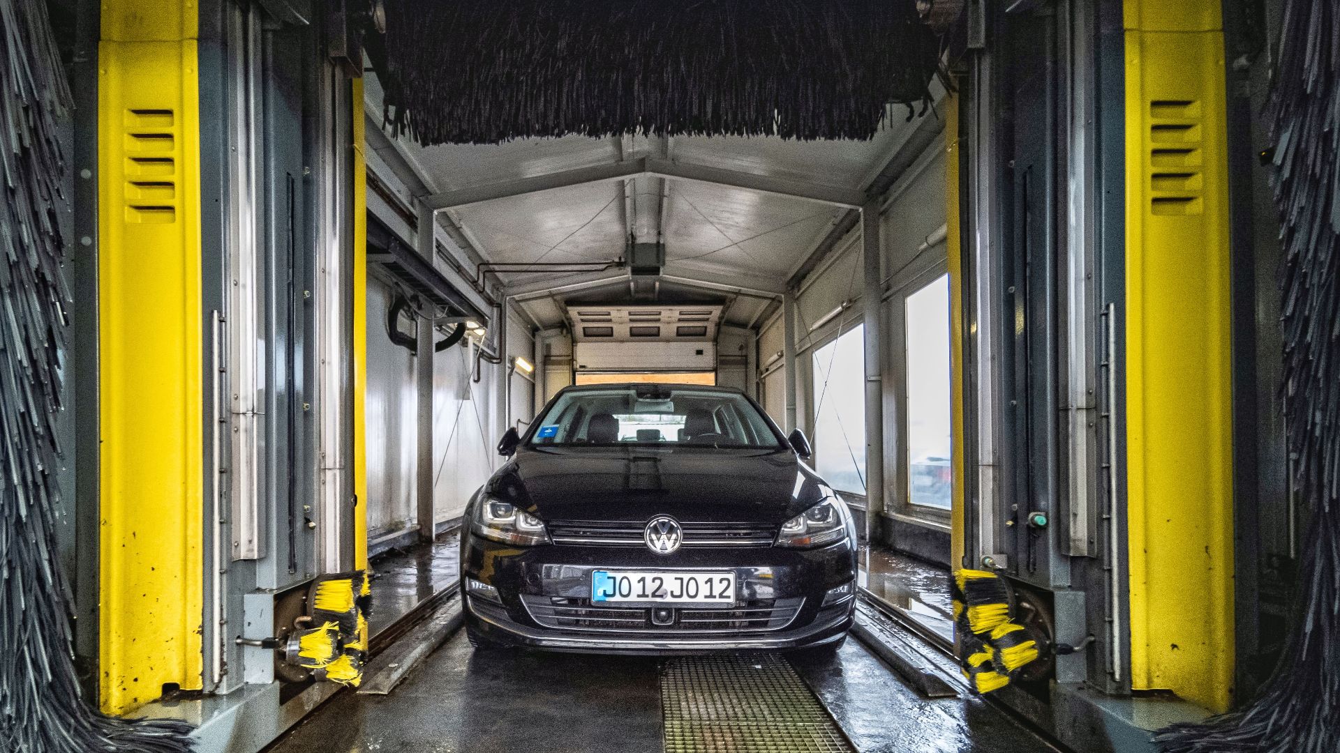 A black car undergoing a thorough cleaning in an automated car wash facility.